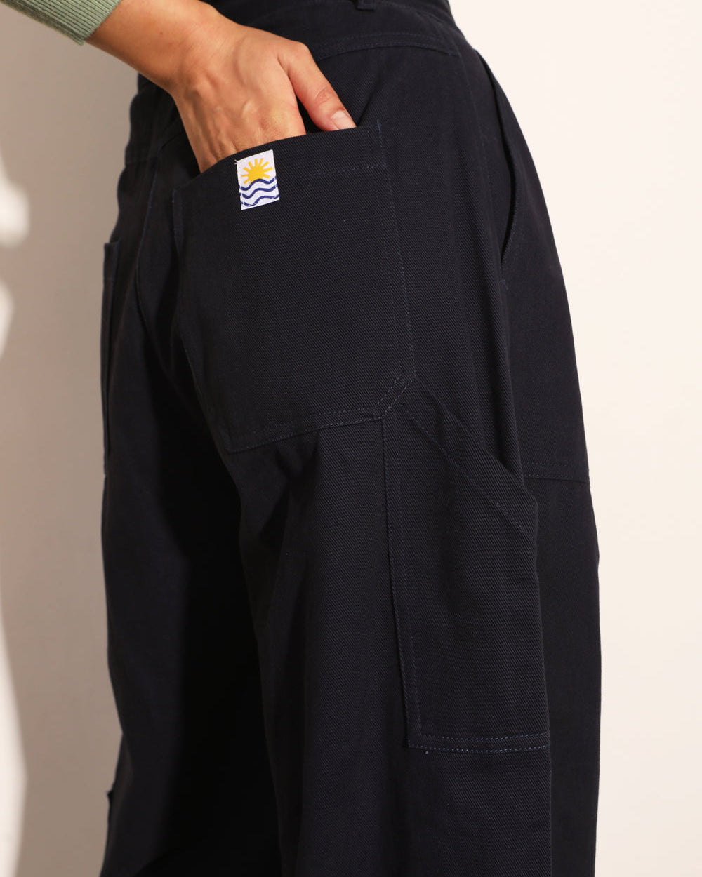 Black pants with a visible brand logo on a beige background