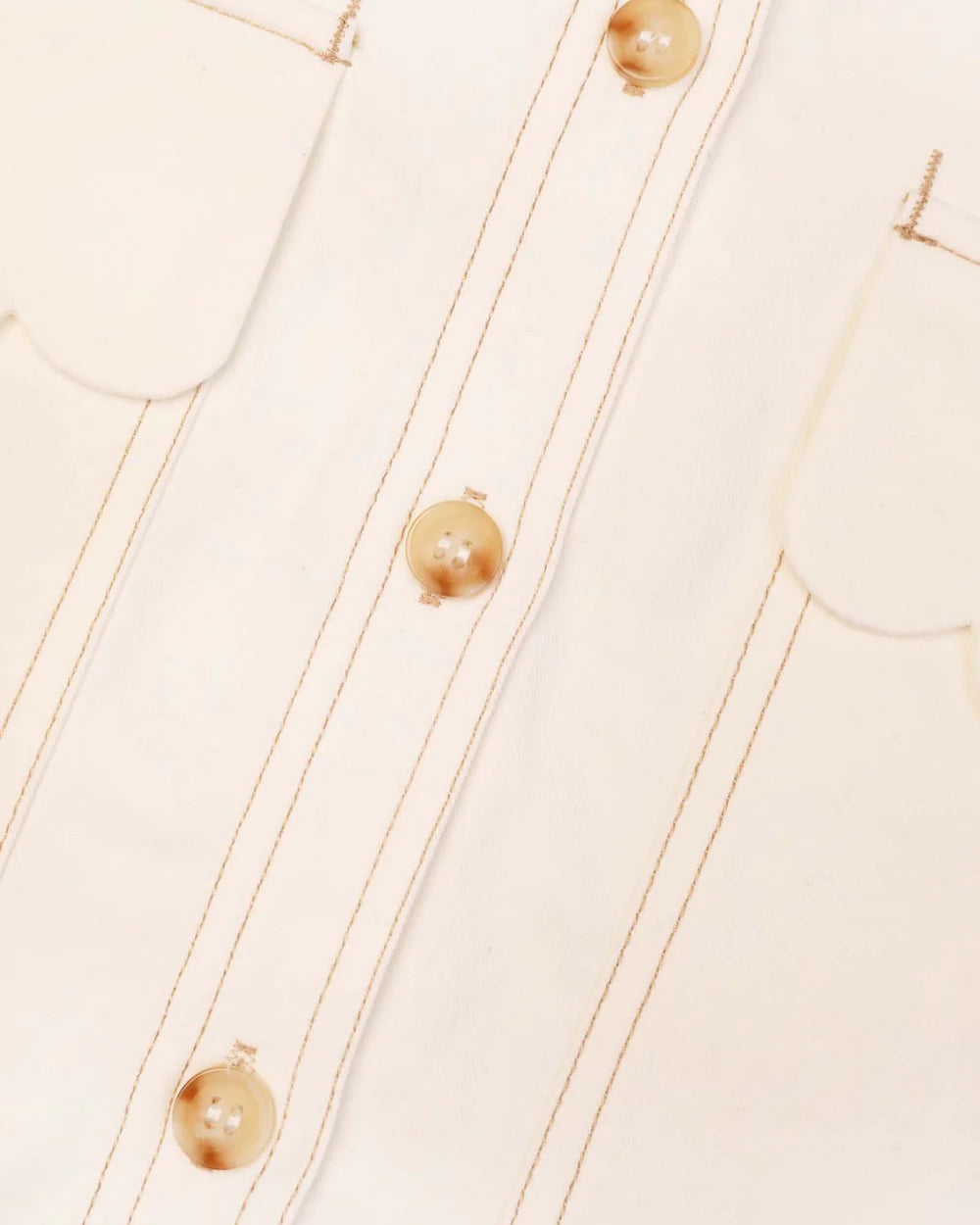Close-up of a beige garment with buttons and stitching details