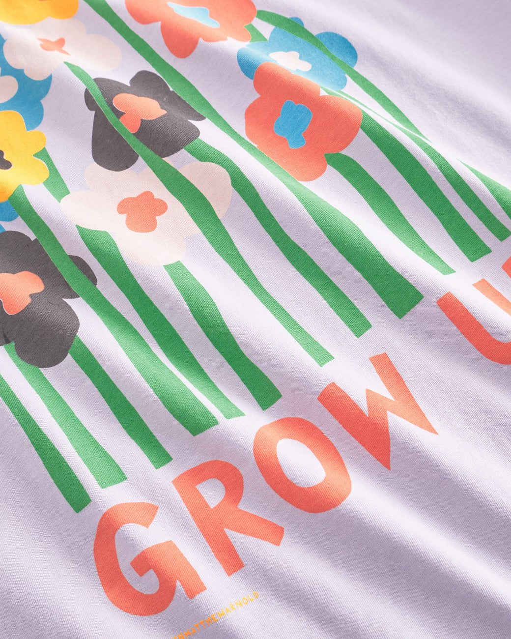 A relaxed fit purple T-shirt with a graphic of flowers and the text 'GROW UP' designed by Luke John Arnold.