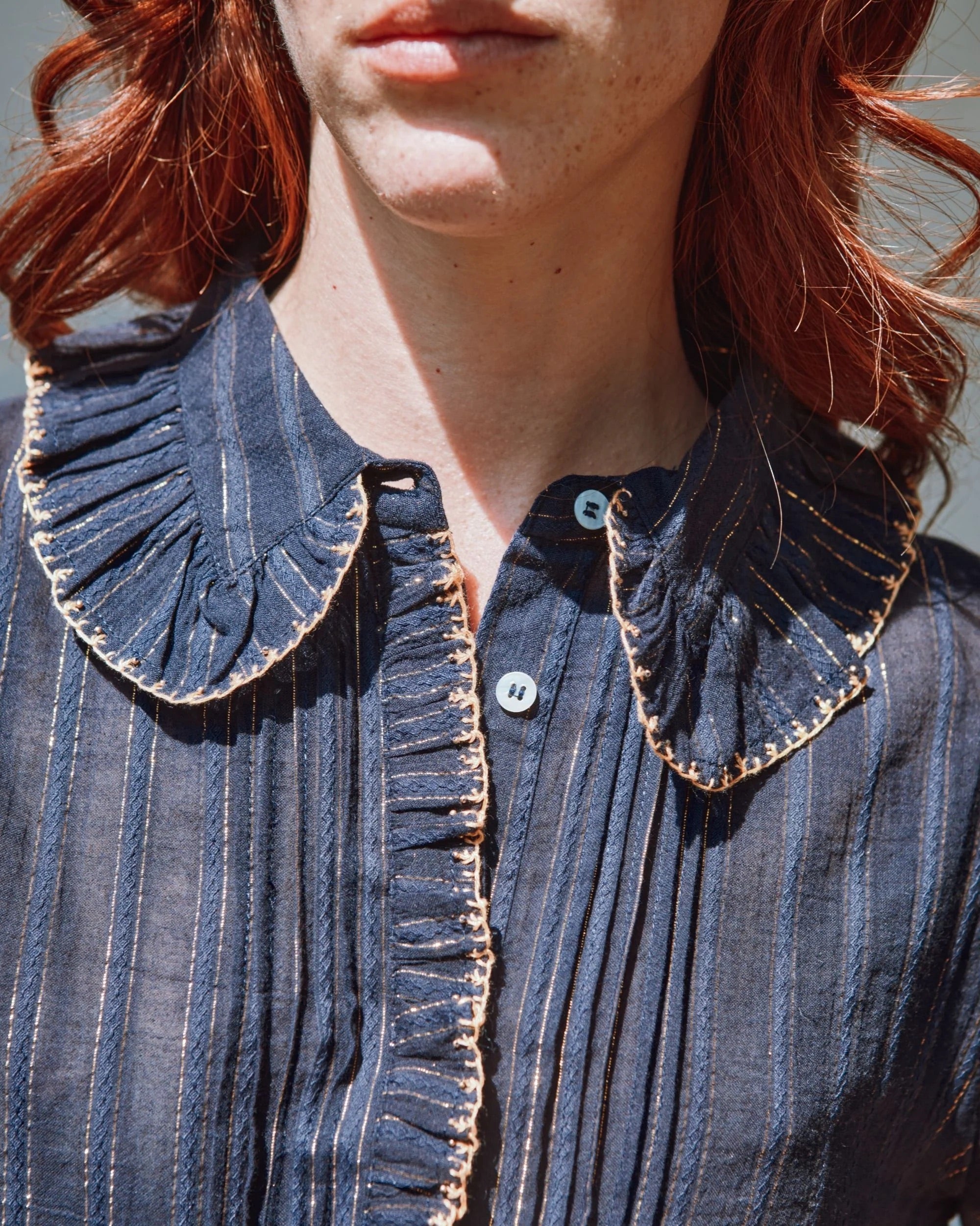 Close-up of a person wearing a blue striped shirt with a ruffled collar.