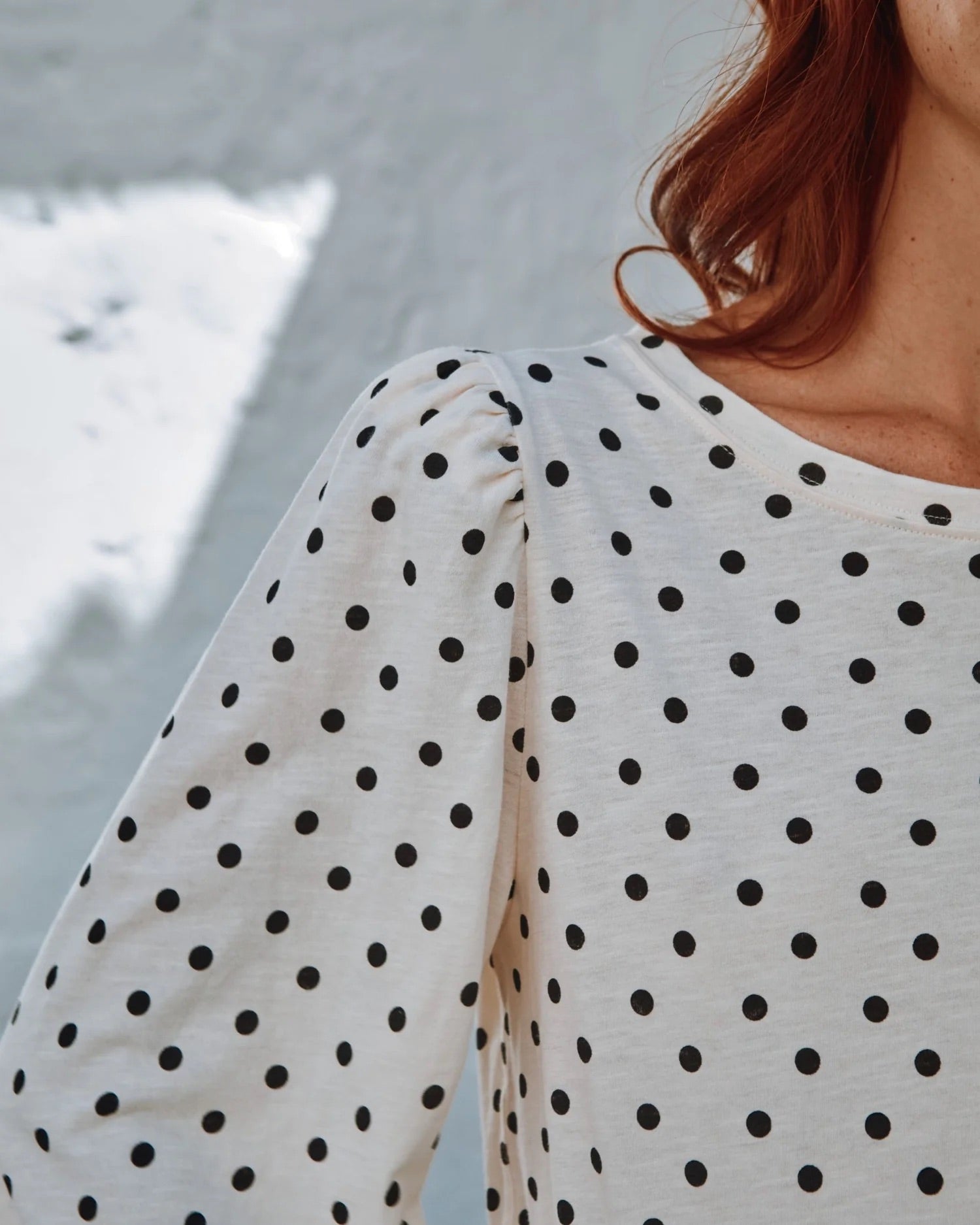 Person wearing a polka dot shirt with a blurred background