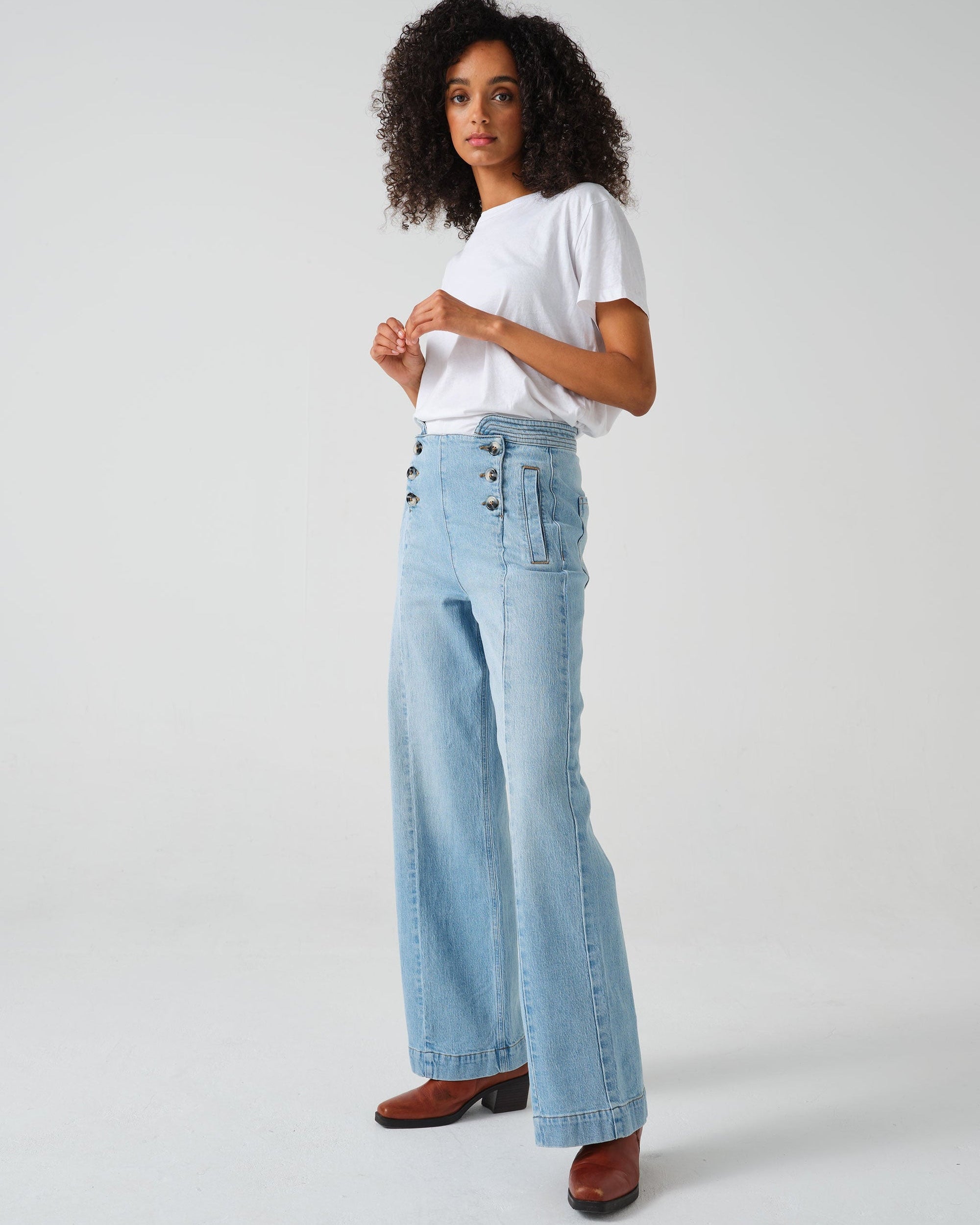 A pair of high-waisted, wide leg jeans with a button-up front in an oceanic blue wash. The jeans are worn with brown ankle boots.