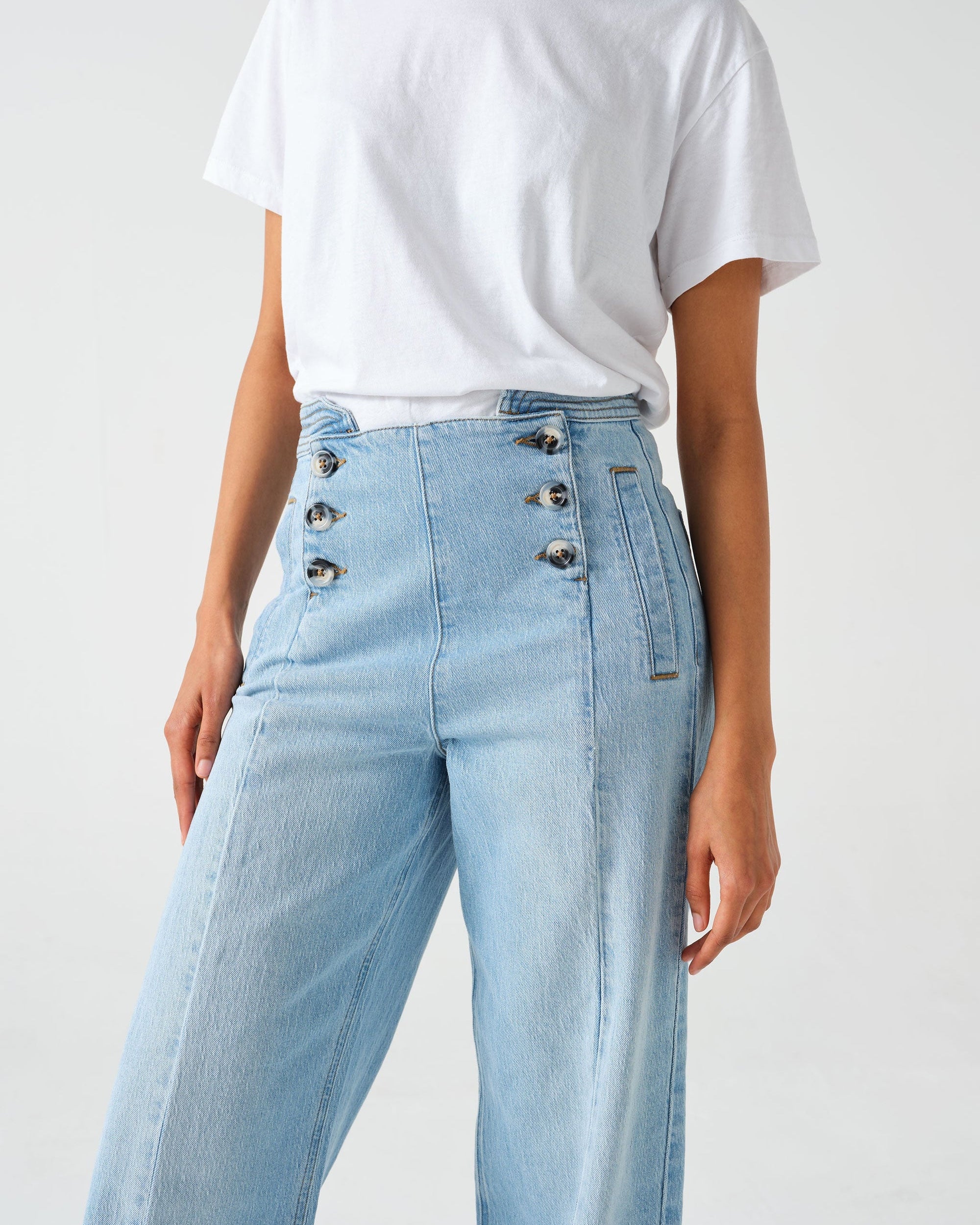 A pair of high-waisted, wide leg jeans with a button-up front in an oceanic blue wash. The jeans are worn with brown ankle boots.