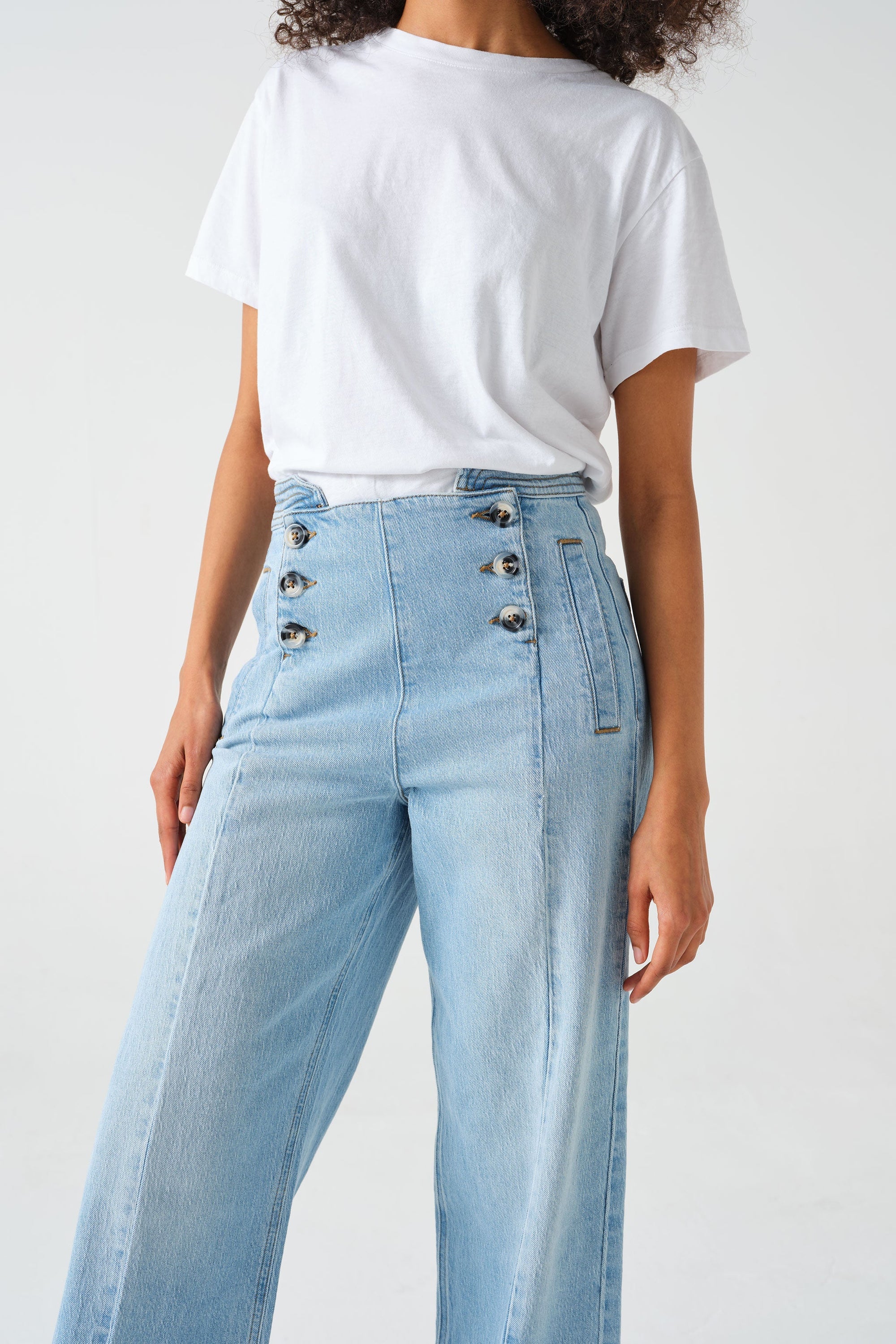 A pair of high-waisted, wide leg jeans with a button-up front in an oceanic blue wash. The jeans are worn with brown ankle boots.
