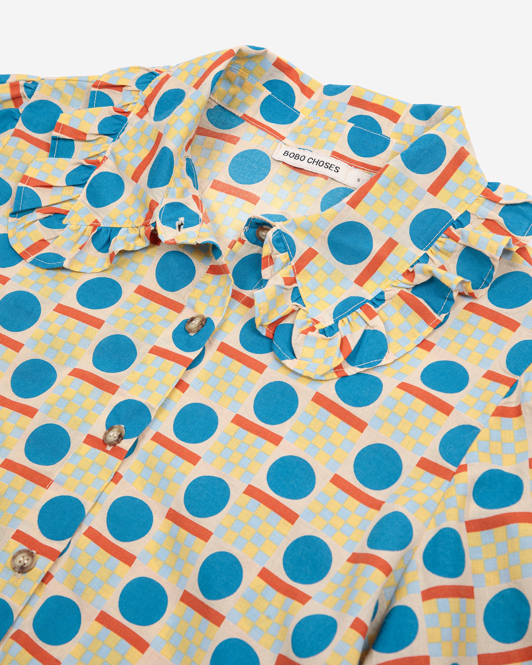 Colorful patterned shirt with blue polka dots and orange accents on a white background