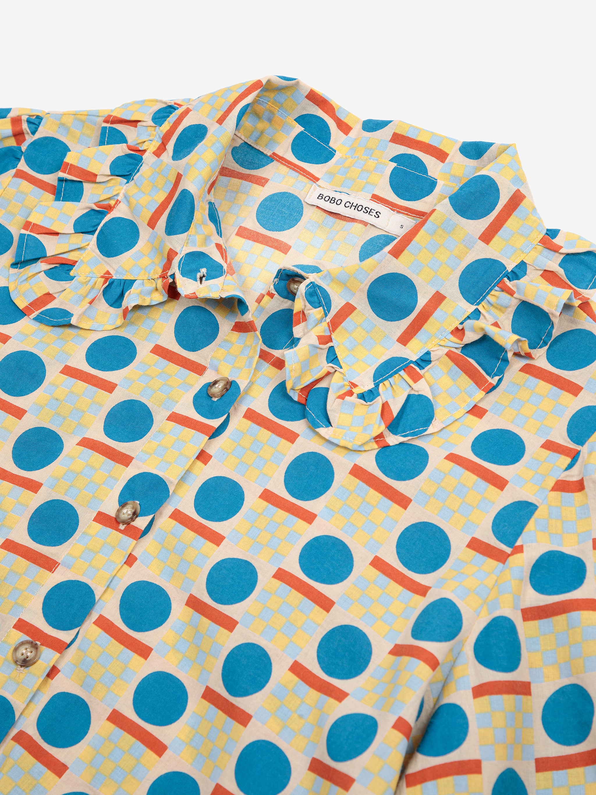 Colorful patterned shirt with blue polka dots and orange accents on a white background