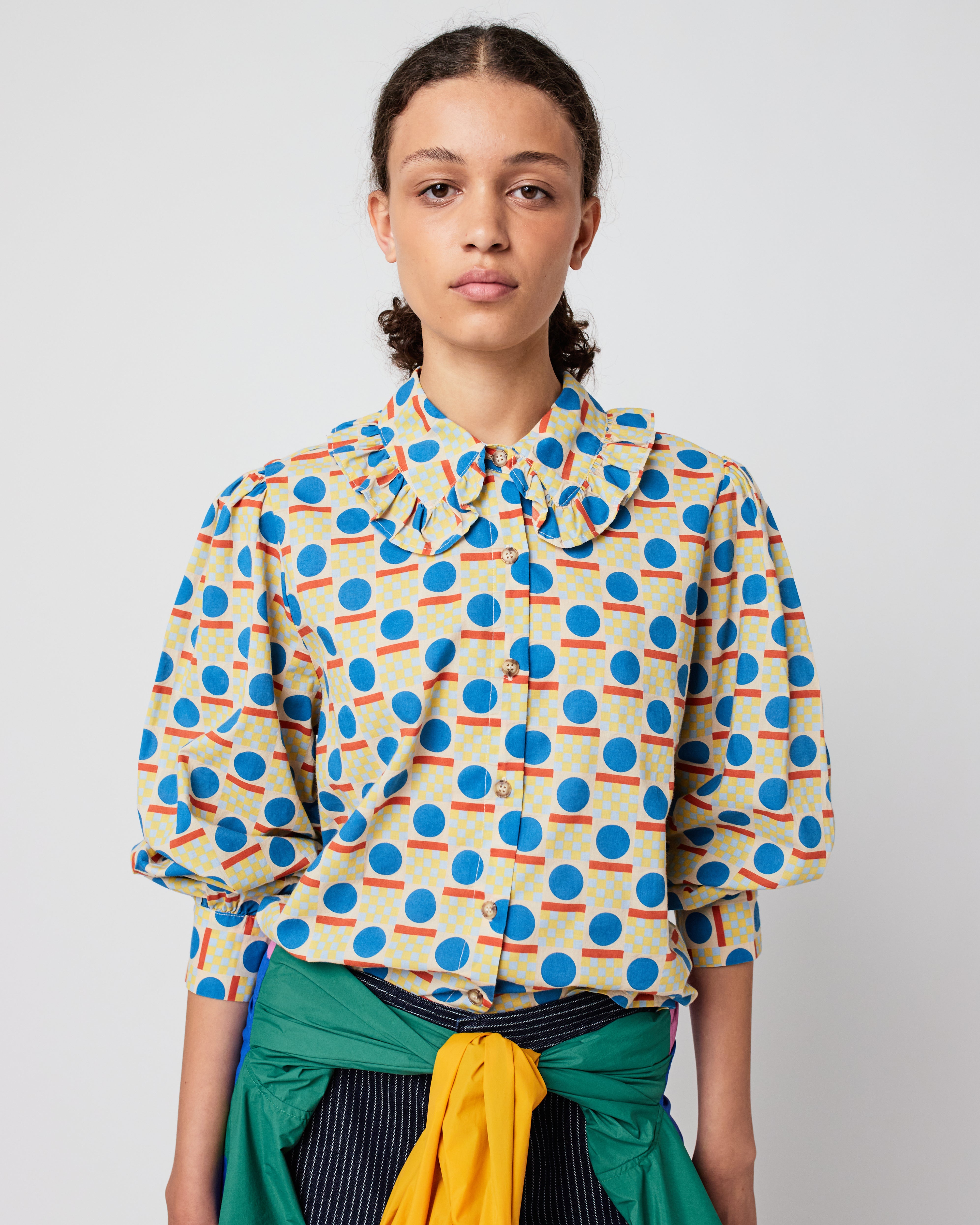Woman wearing a colorful patterned blouse against a plain background