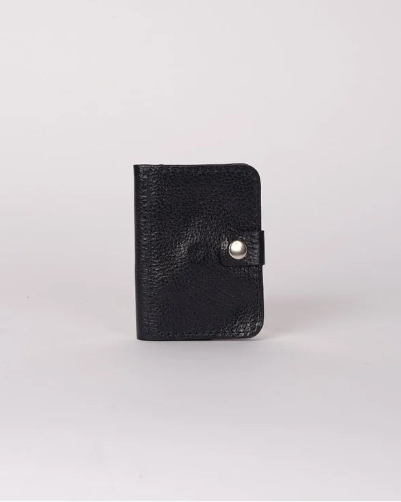 A small black textured leather card holder or wallet with a snap button closure, standing upright on a light gray background.