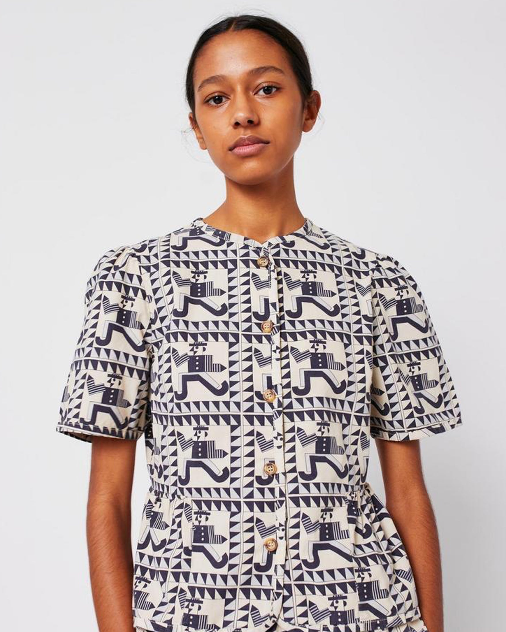 Person wearing a patterned shirt with geometric design on a plain background