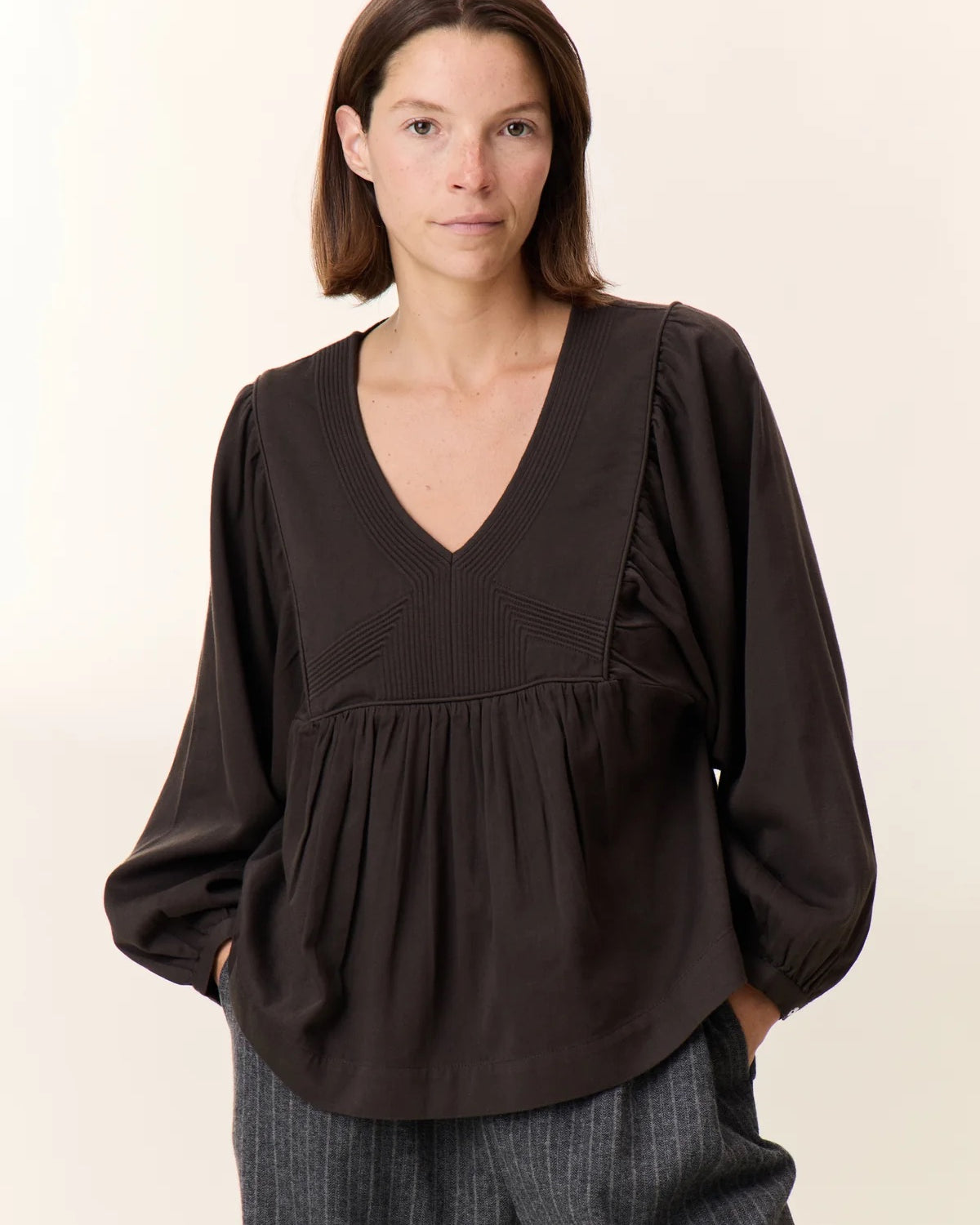 Woman wearing a black blouse with a plain background