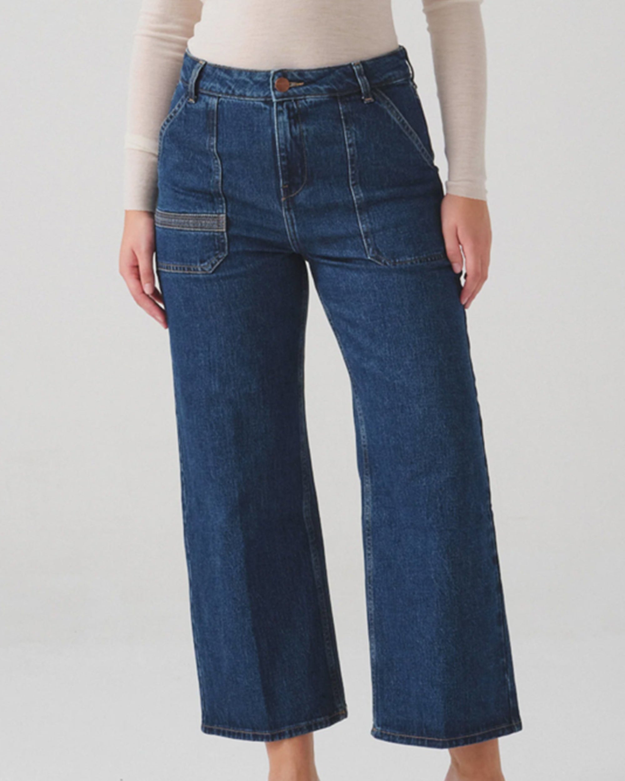 Person wearing blue jeans on a plain background