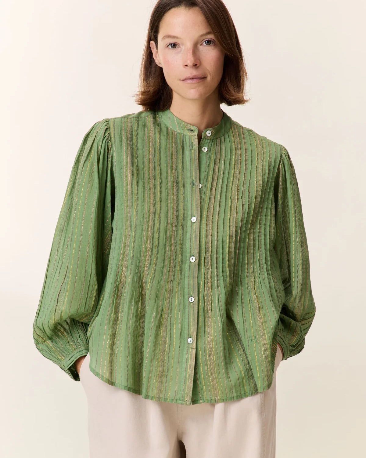 Woman wearing a green striped shirt against a plain background