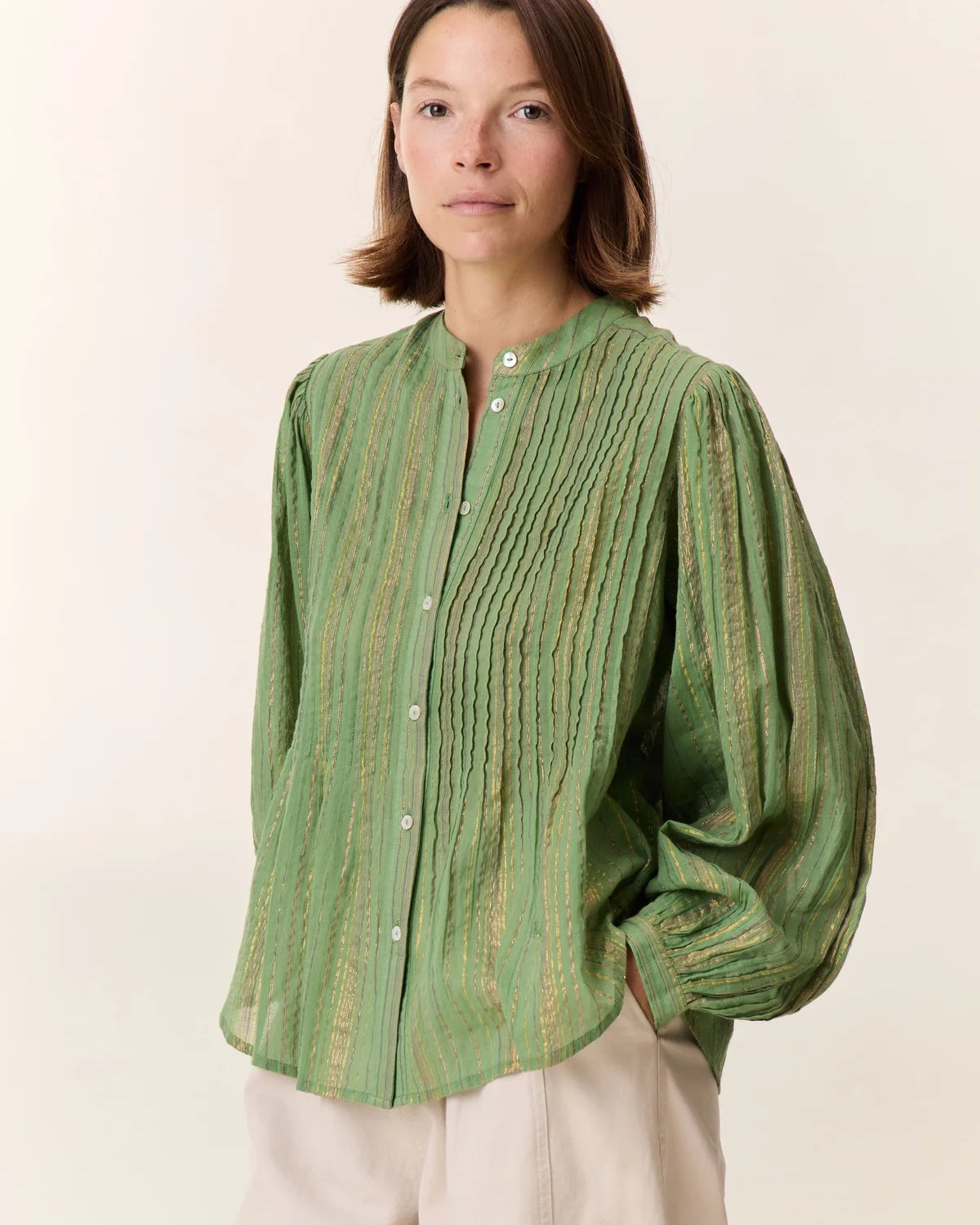 Woman wearing a green striped shirt against a white background