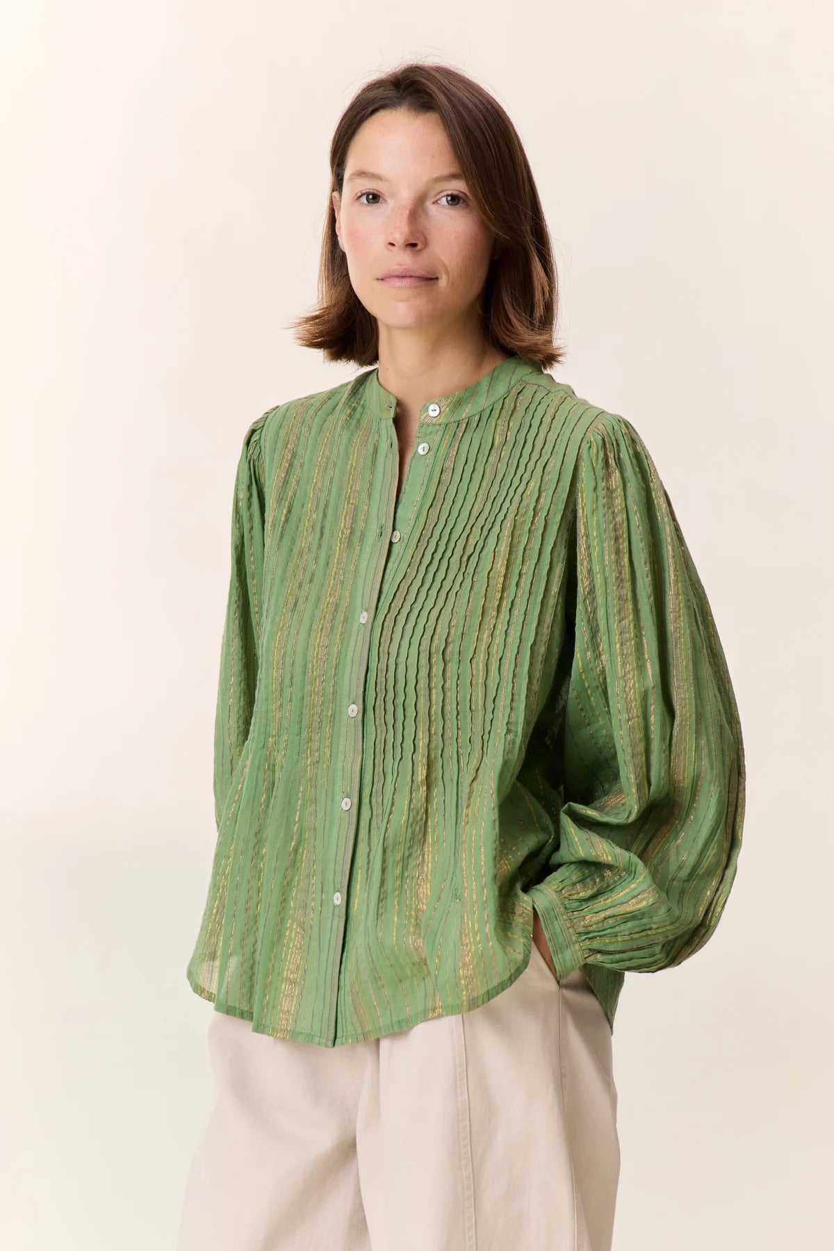 Woman wearing a green striped shirt against a white background