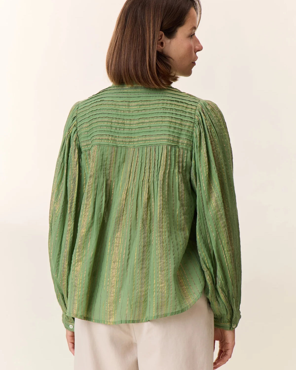 Woman wearing a green patterned blouse against a white background