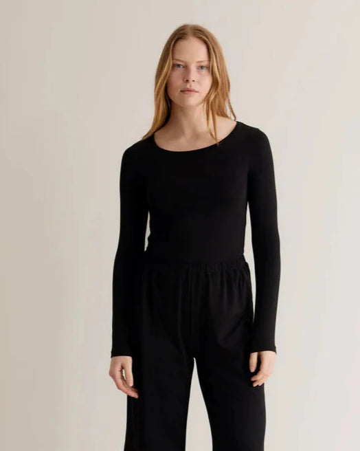 A woman wearing a black long-sleeve top with a relaxed fit and a crew neck.
