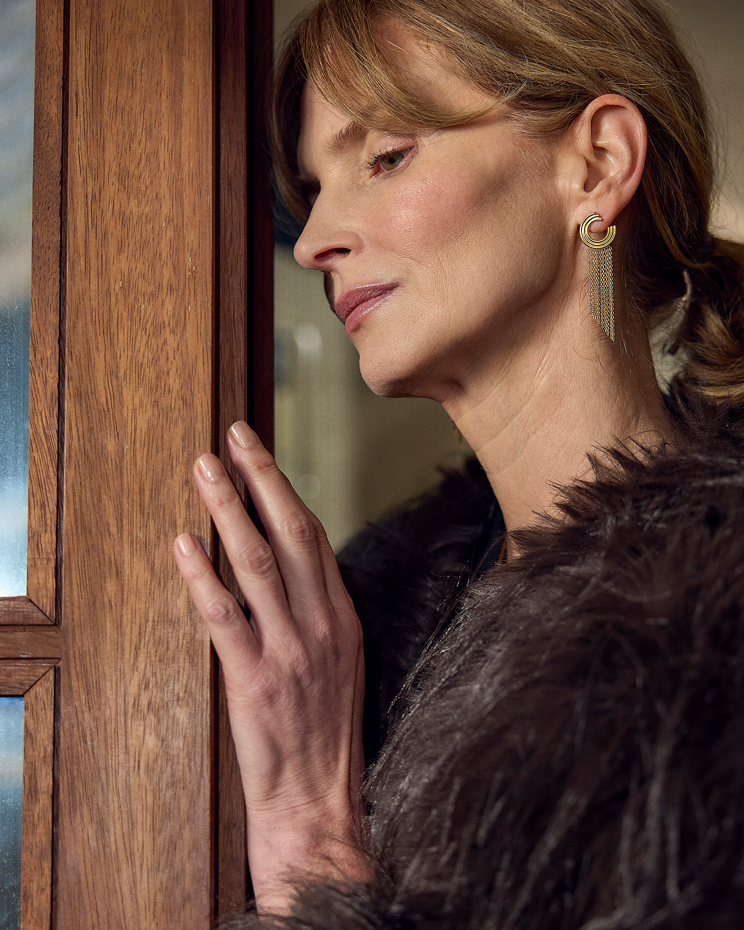 Woman in a fur coat peering through a wooden door