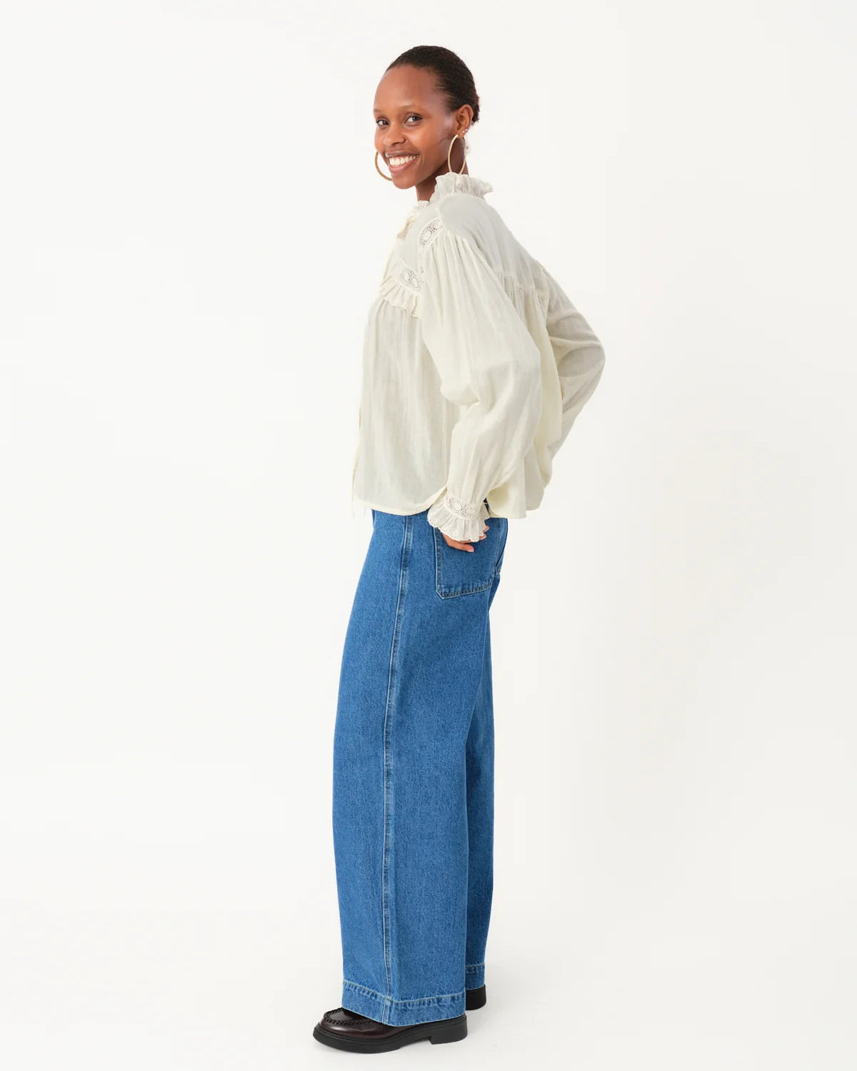 Person wearing a white blouse and blue jeans on a white background
