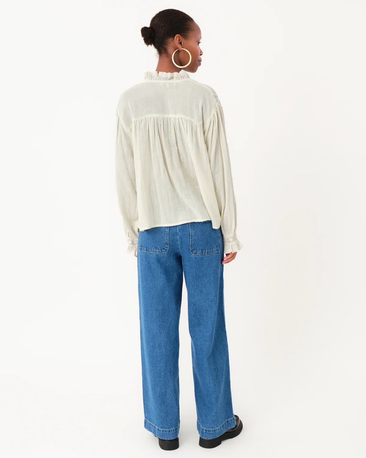 Person wearing a white blouse and blue jeans on a white background