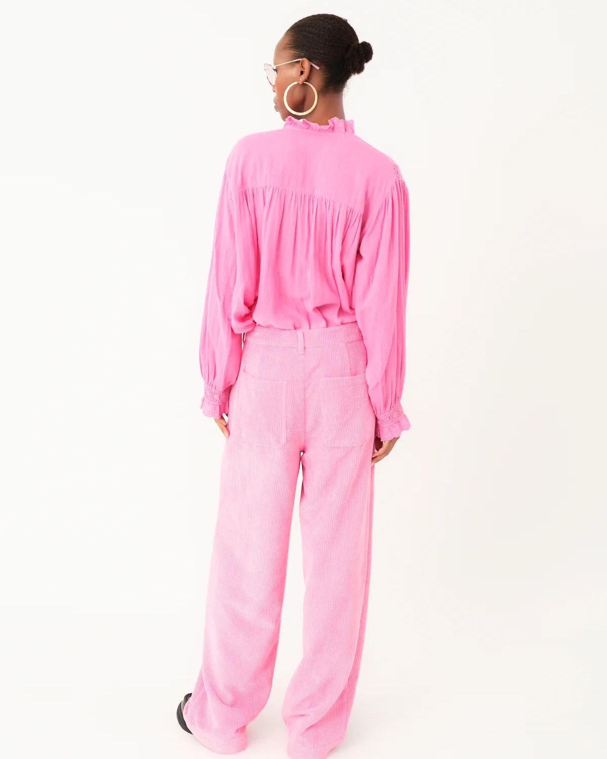 Person wearing a bright pink outfit on a white background