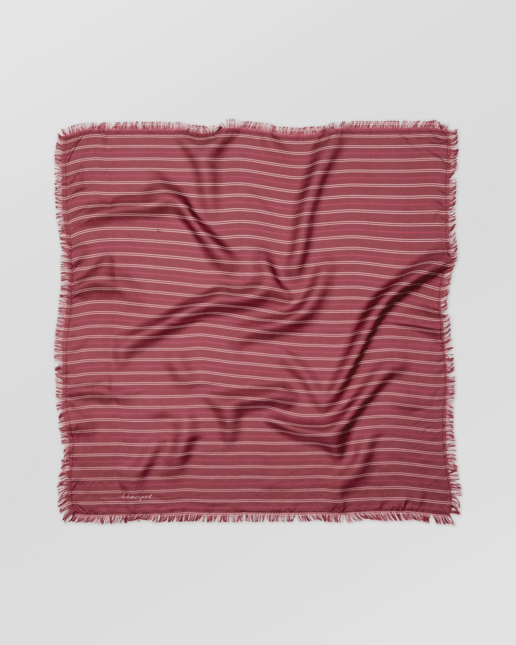 Striped fabric square with frayed edges on a light gray background