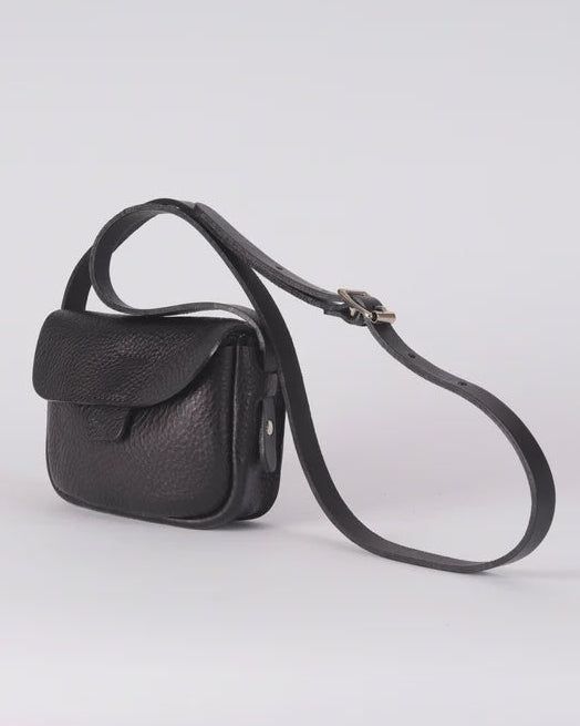 A small black leather crossbody bag with a long adjustable strap, shown on a light gray studio background.