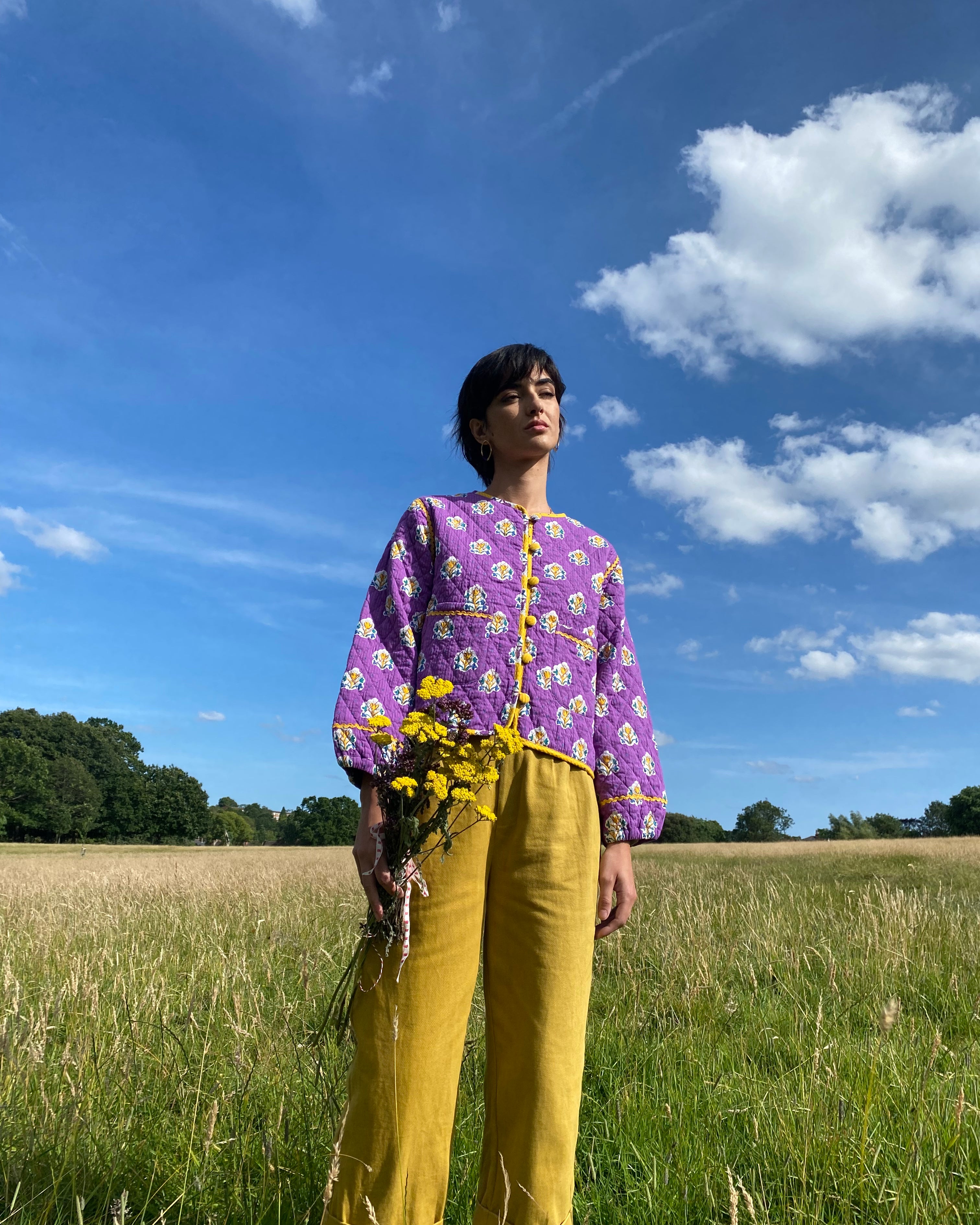 A pair of ochre pleat front trousers with a tab front opening and back jet pockets.