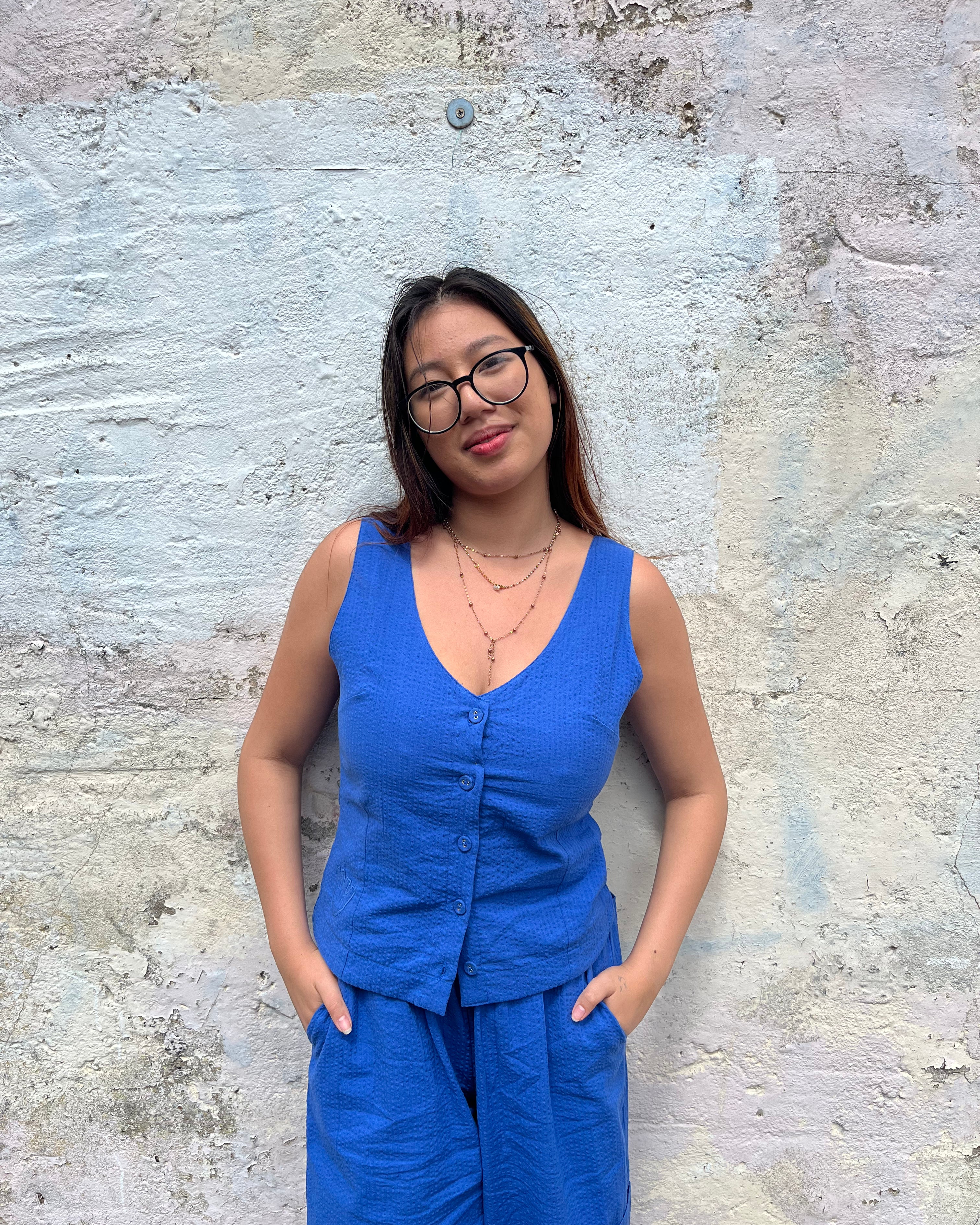 Woman in a blue outfit standing against a textured wall