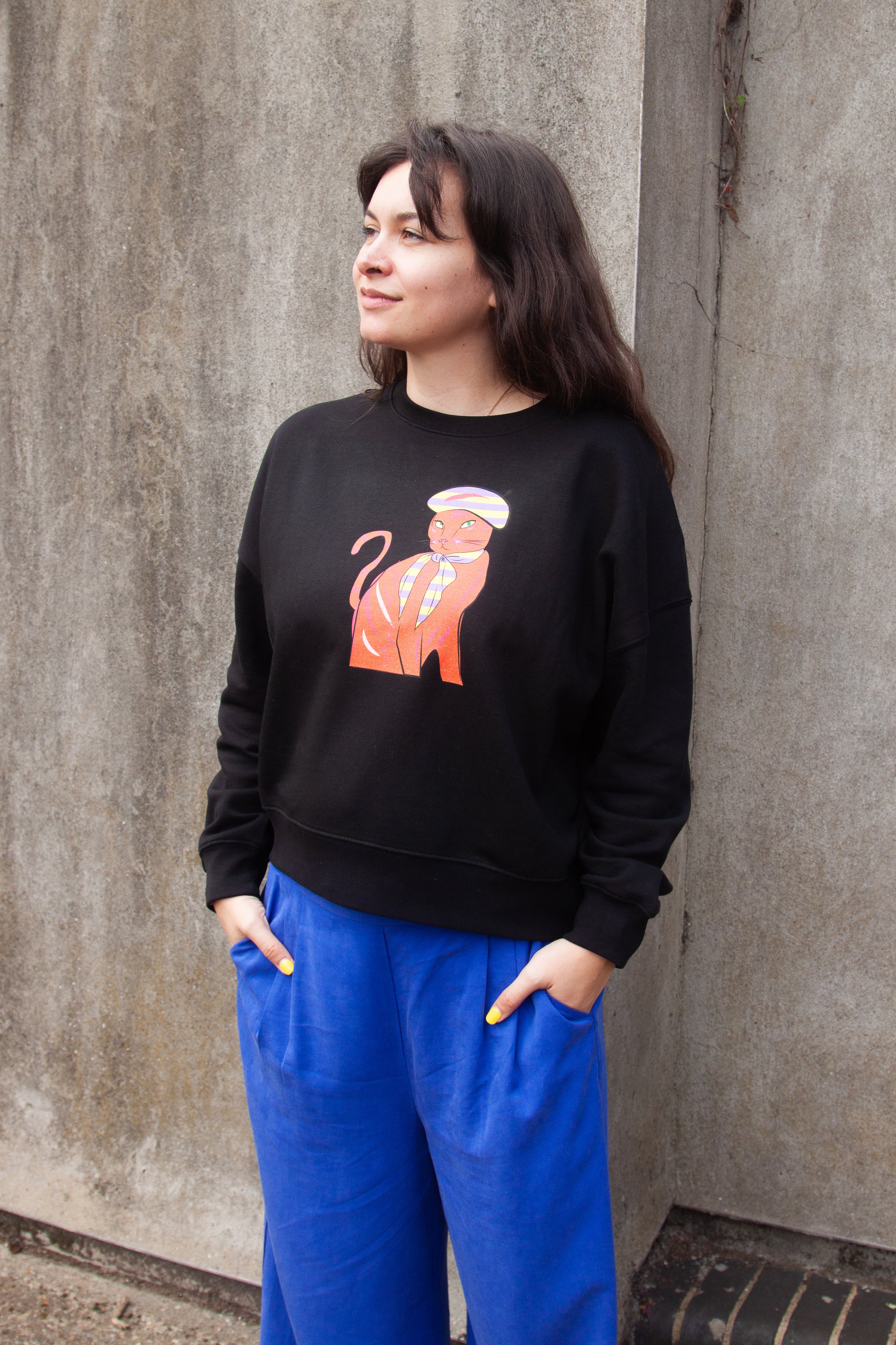 Black sweatshirt with a graphic print of a red and orange cat wearing a Parisian style hat and scarf.