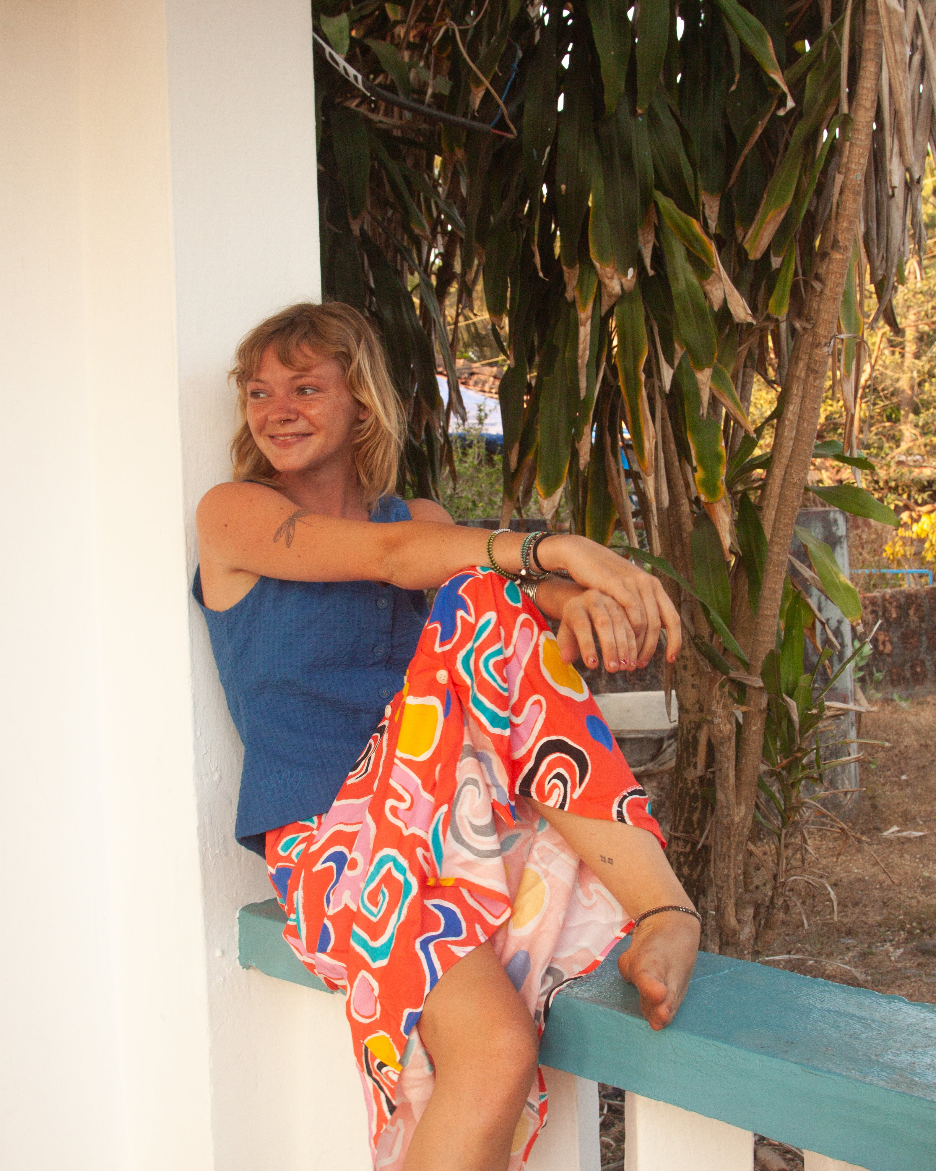 A midi-length orange skirt with a colorful abstract print, featuring side pockets and elasticated back waist.