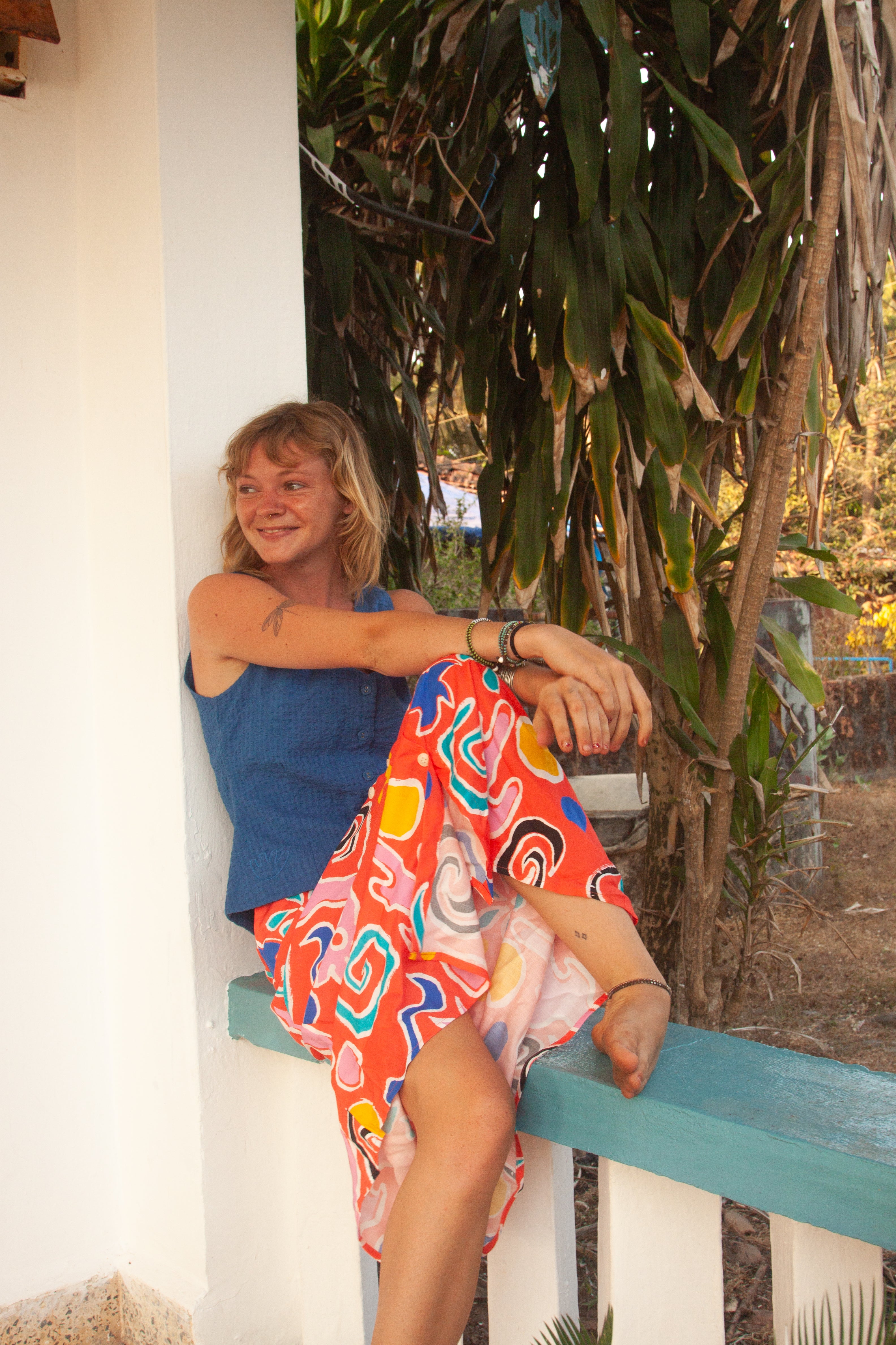 A midi-length orange skirt with a colorful abstract print, featuring side pockets and elasticated back waist.