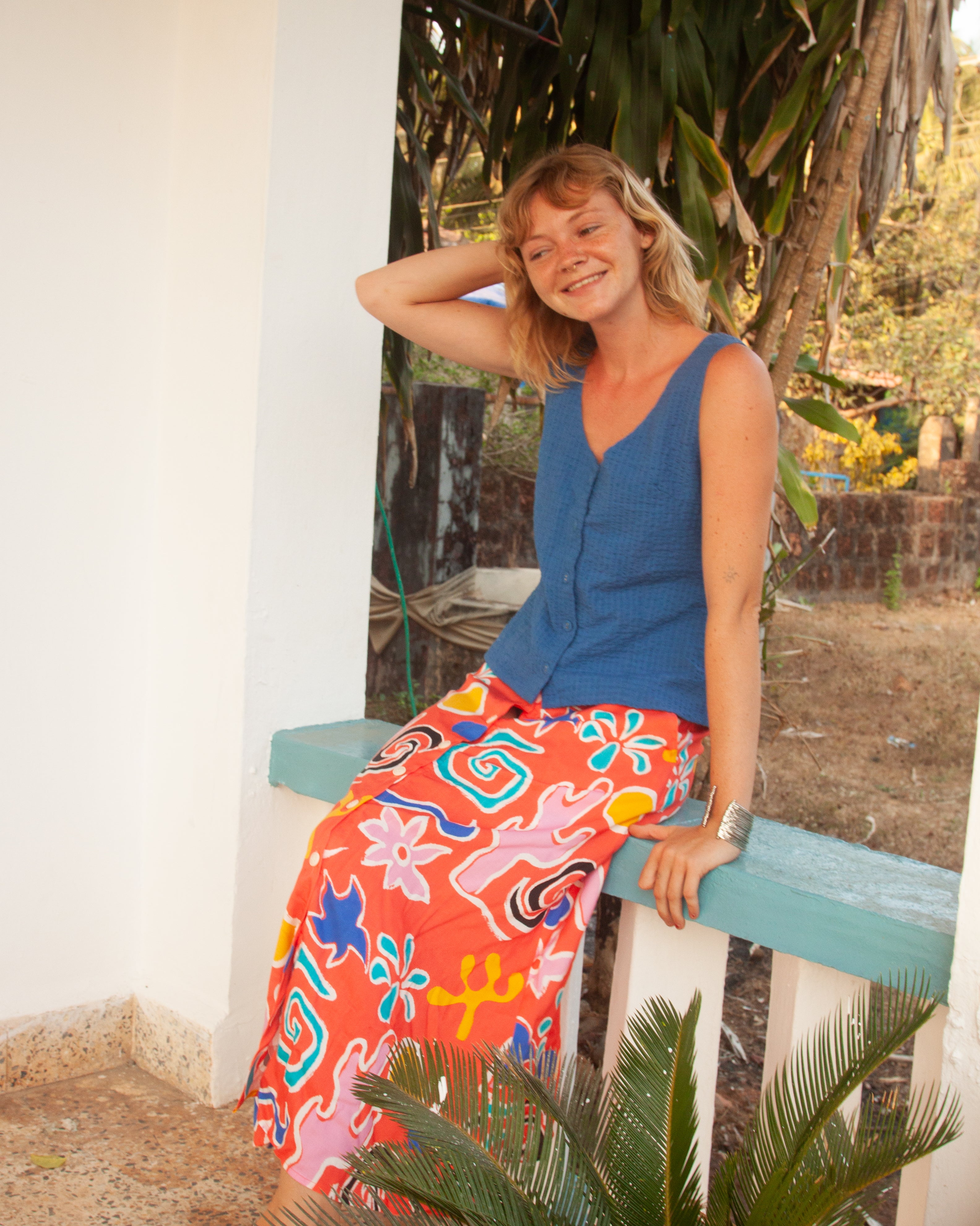 A midi-length orange skirt with a colorful abstract print, featuring side pockets and elasticated back waist.
