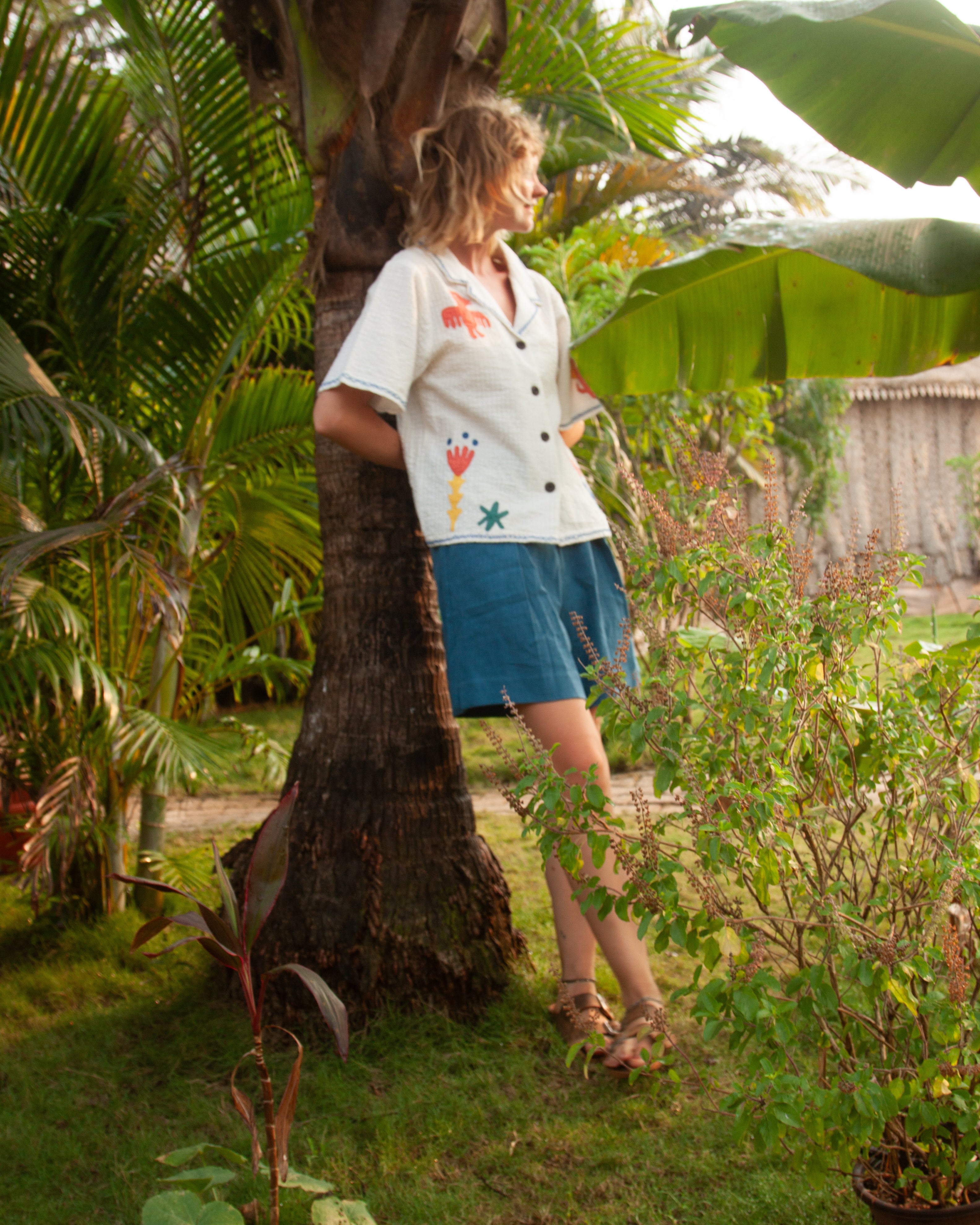 Woman in a garden leaning against a tree