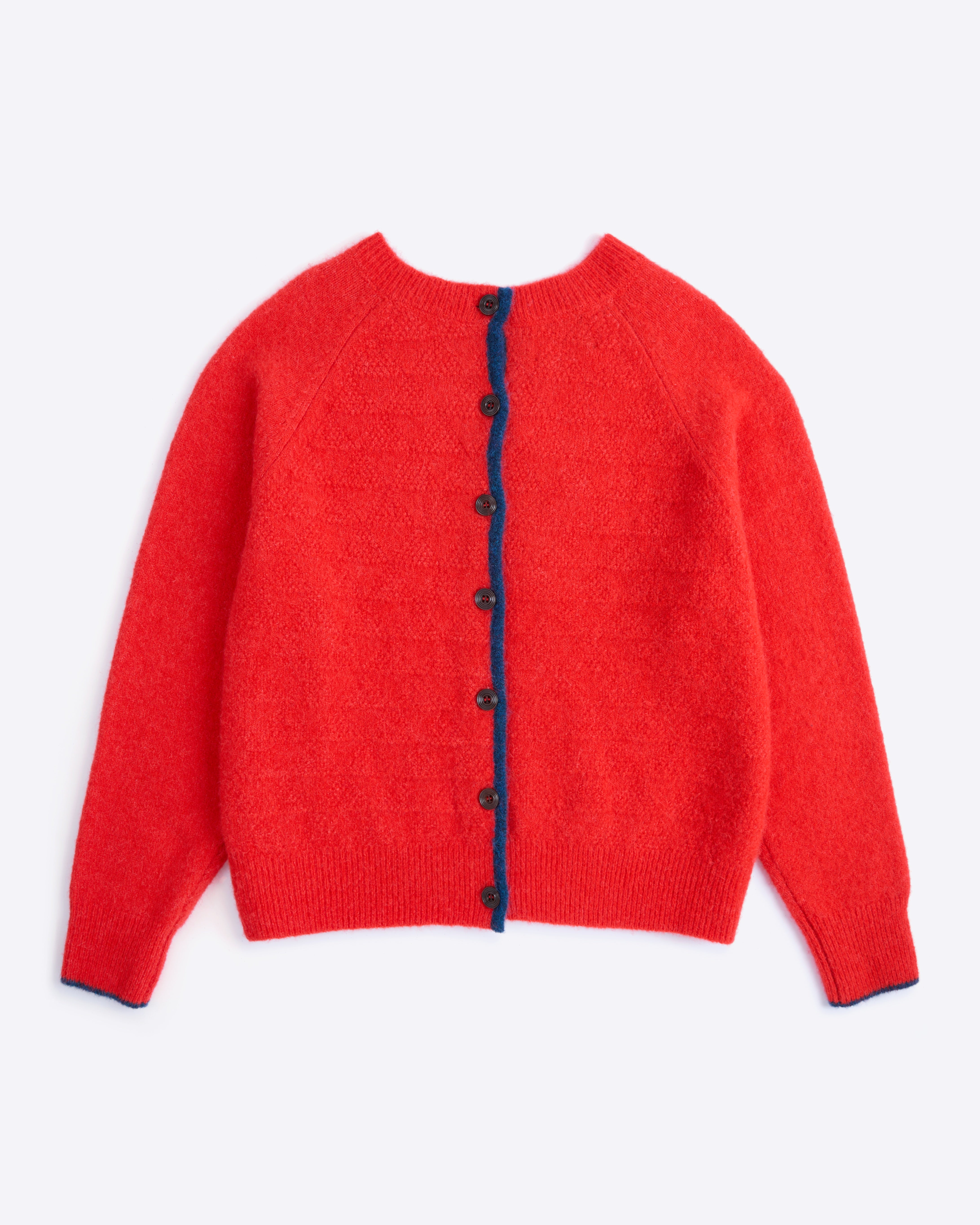 Red cardigan with navy buttons on a white background