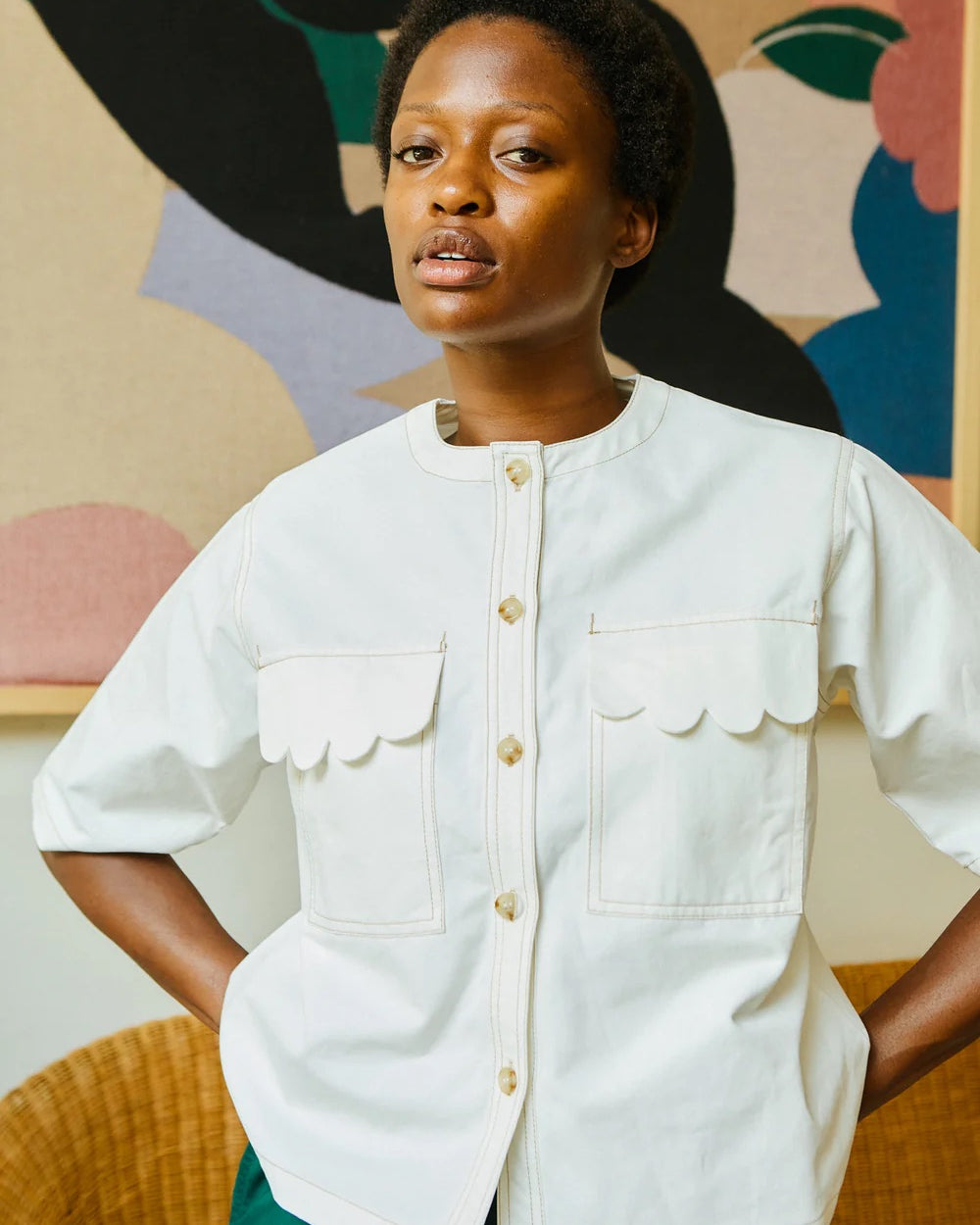 Woman wearing a white shirt with a colorful abstract painting in the background