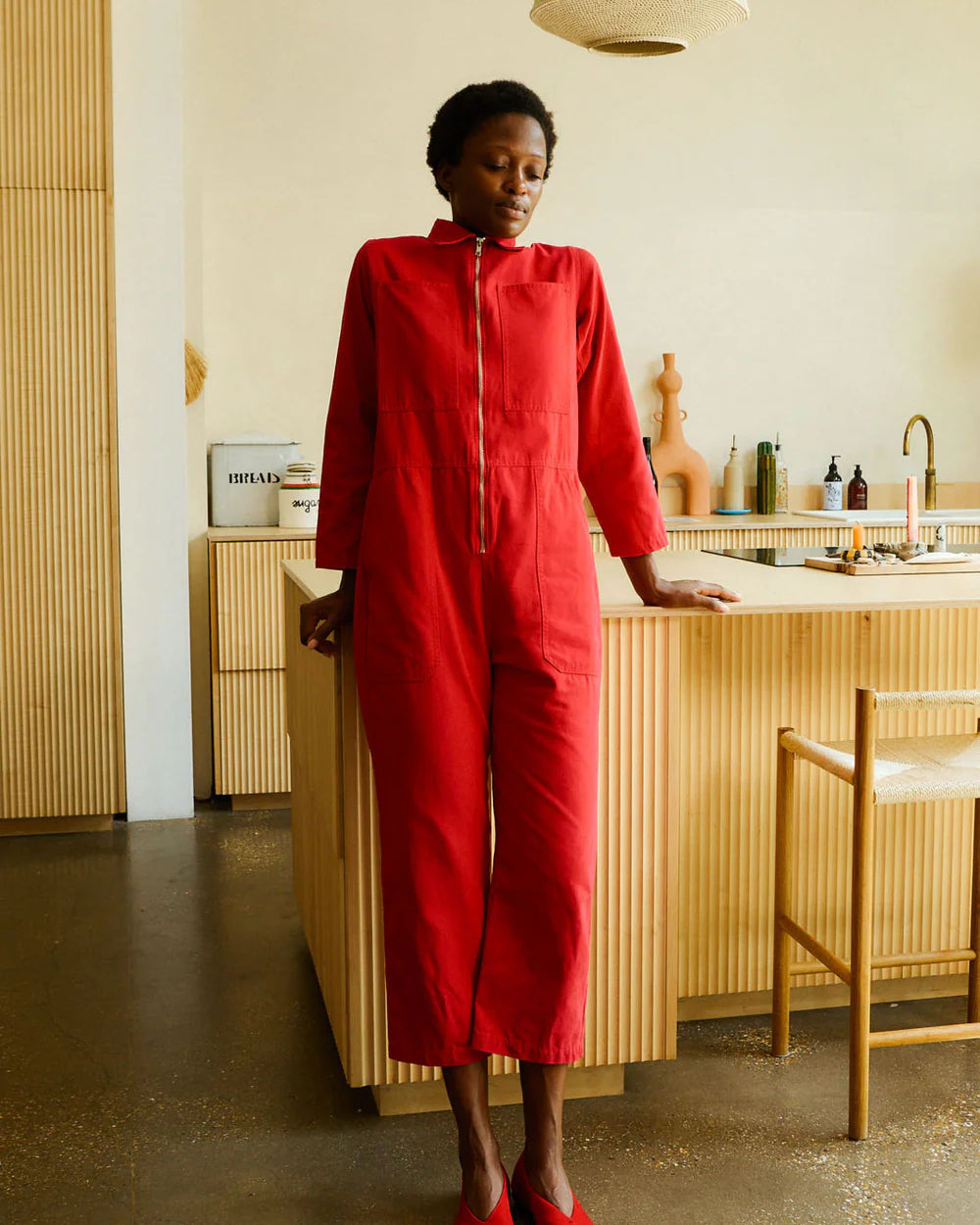 Person wearing a red outfit standing in a modern kitchen.