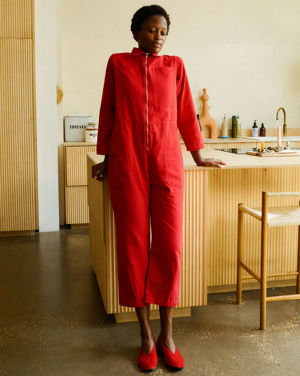 Person wearing a red outfit standing in a modern kitchen.