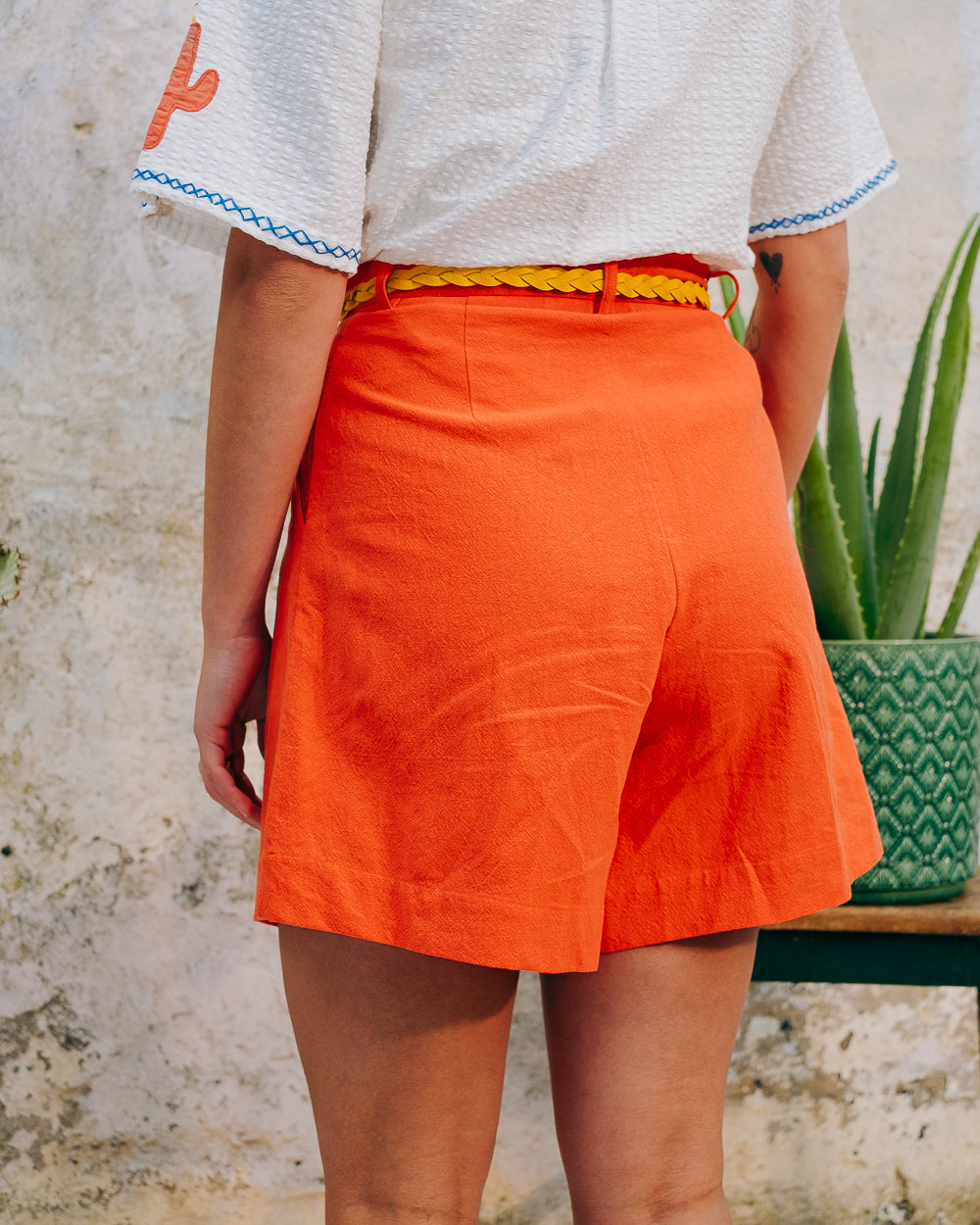 A pair of high-waisted, mid-length, tailored tomato shorts made from a cotton and linen mix.