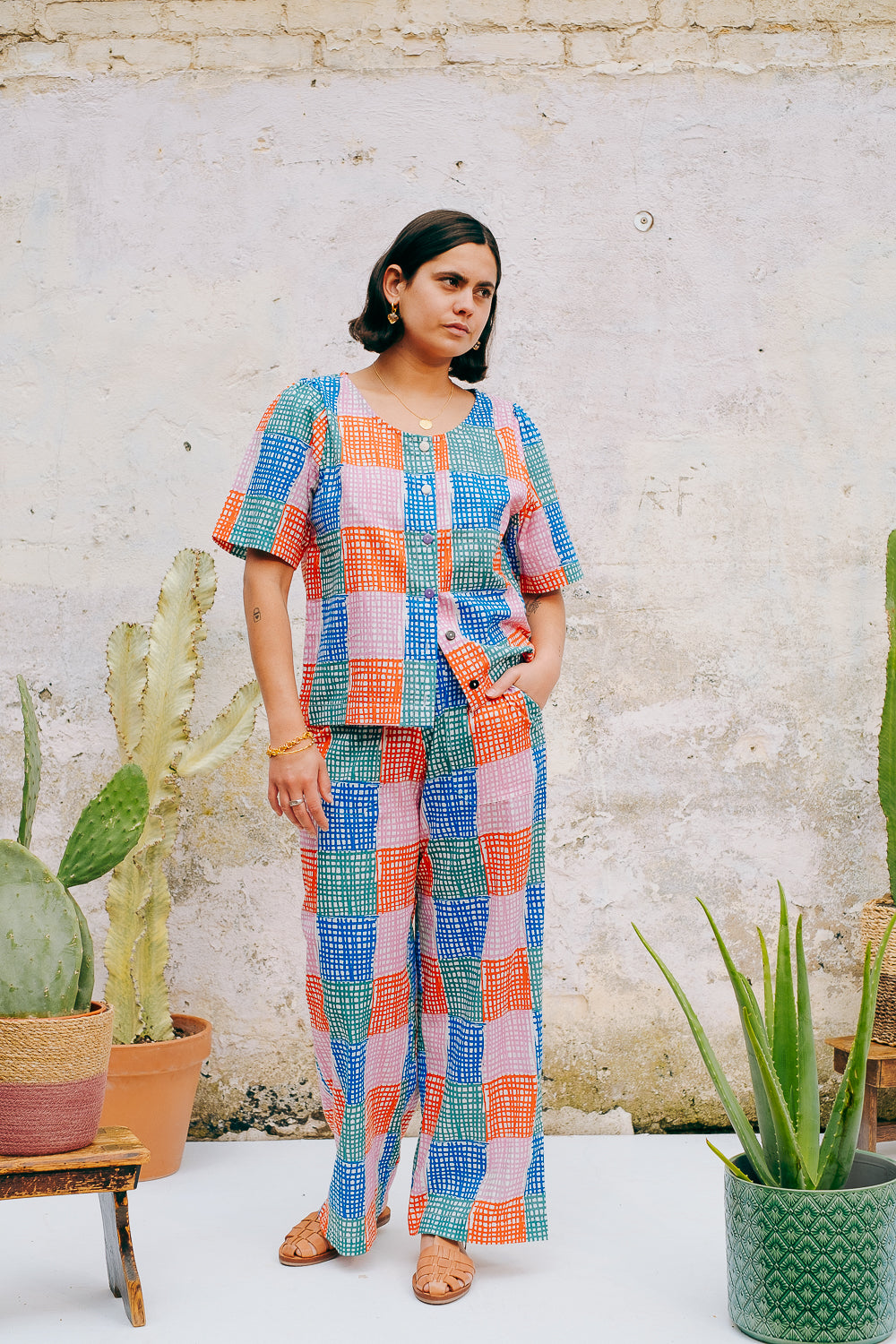 A pair of straight leg trousers with a multicolored grid check pattern. The trousers have a flat front, elasticated waist at the back, and side patch pockets.