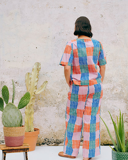 A pair of straight leg trousers with a multicolored grid check pattern. The trousers have a flat front, elasticated waist at the back, and side patch pockets.