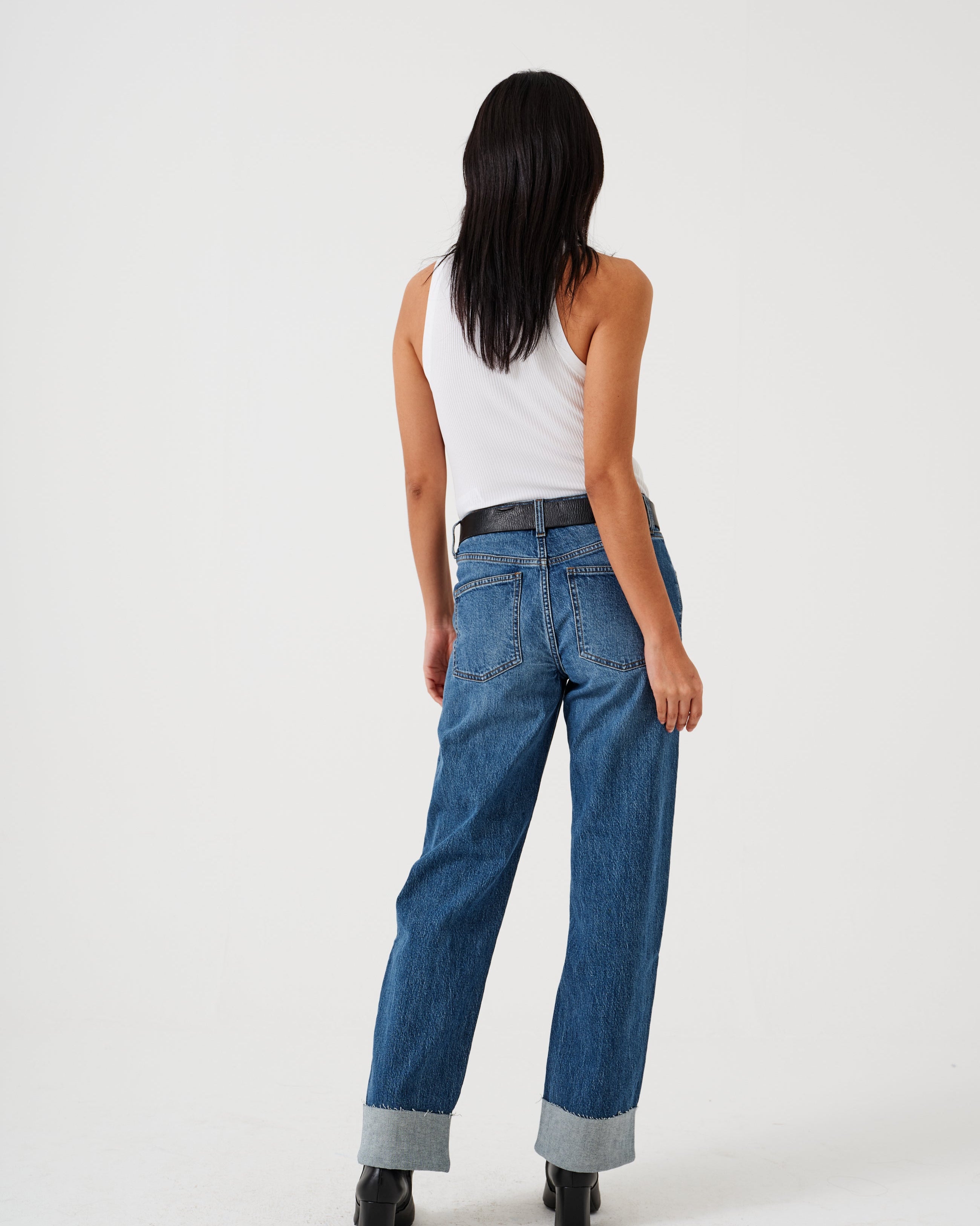 A pair of blue denim jeans with a frayed hem and a deep turn-up at the cuffs, featuring a straight leg cut and mid-rise waist.