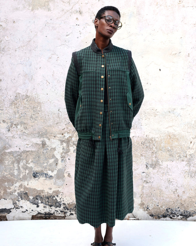 Person wearing Lowie Green Check Bomber Jacket standing against a textured wall.