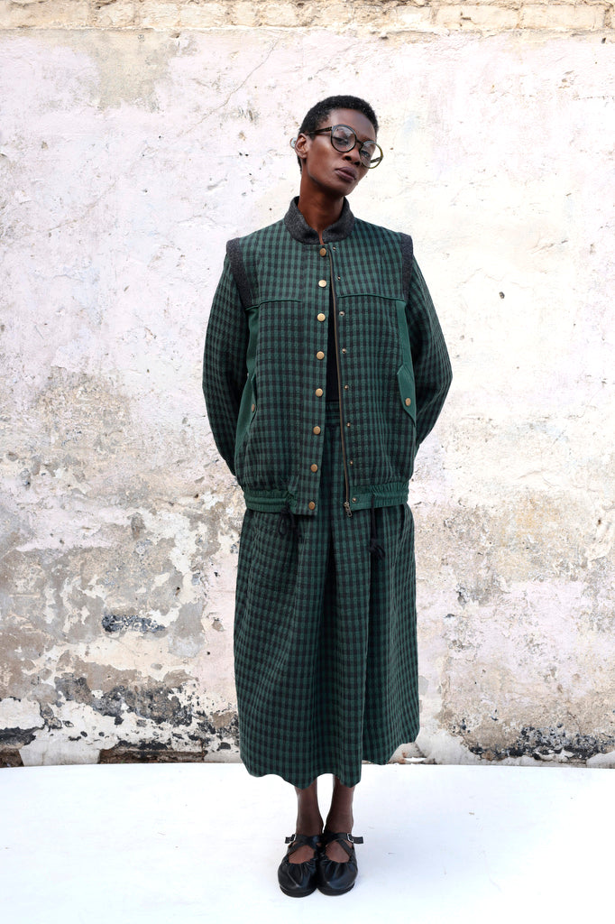 Person wearing Lowie Green Check Bomber Jacket standing against a textured wall.