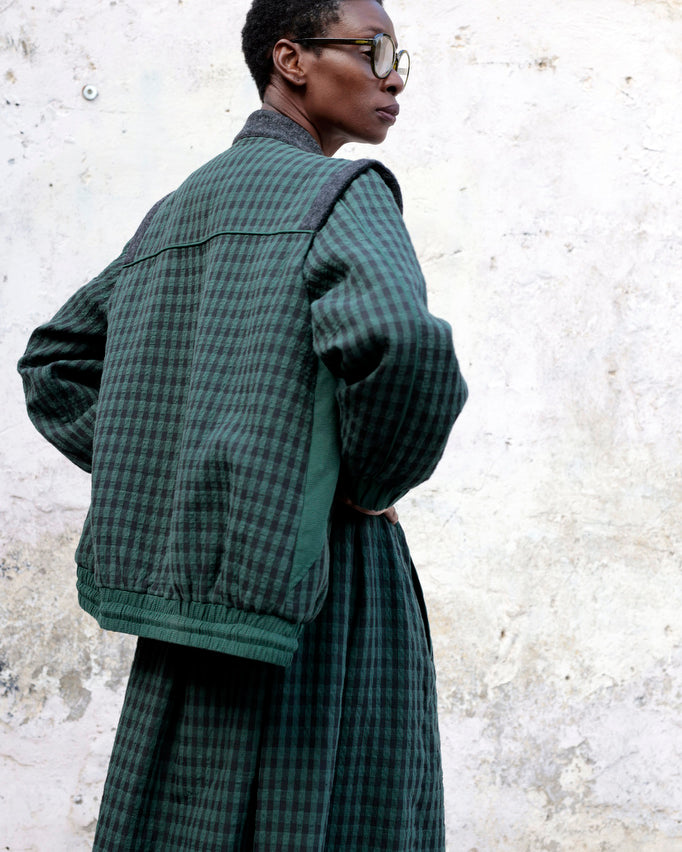 Person wearing Lowie Green Check Bomber Jacket against a textured wall.