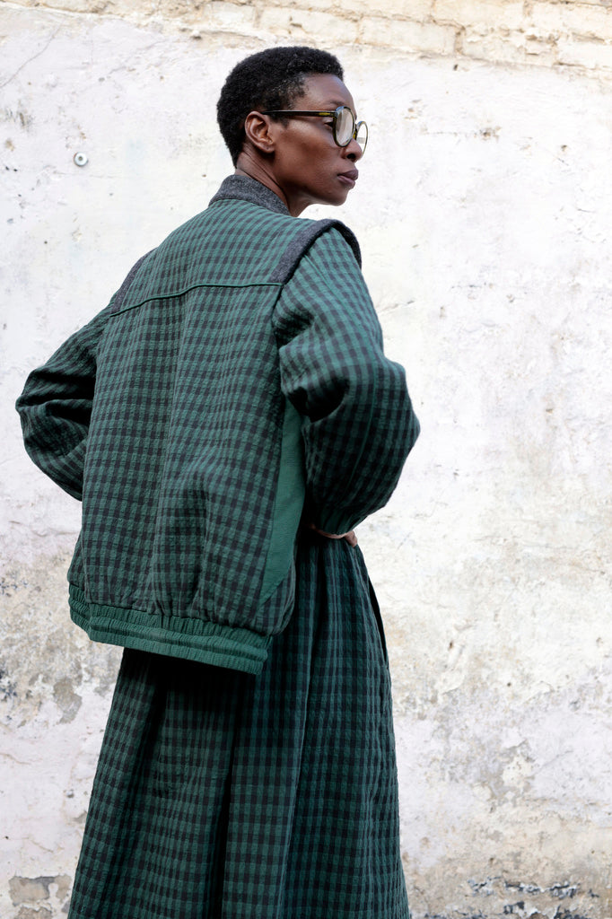 Person wearing Lowie Green Check Bomber Jacket against a textured wall.