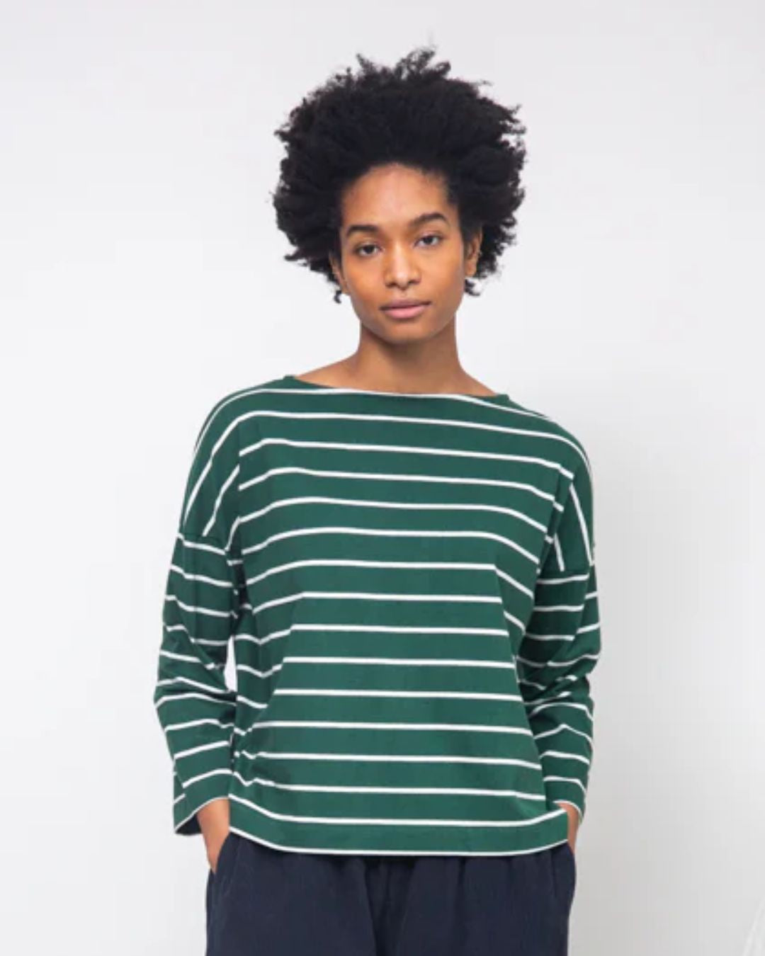 Person wearing a green and white striped sweater on a plain background