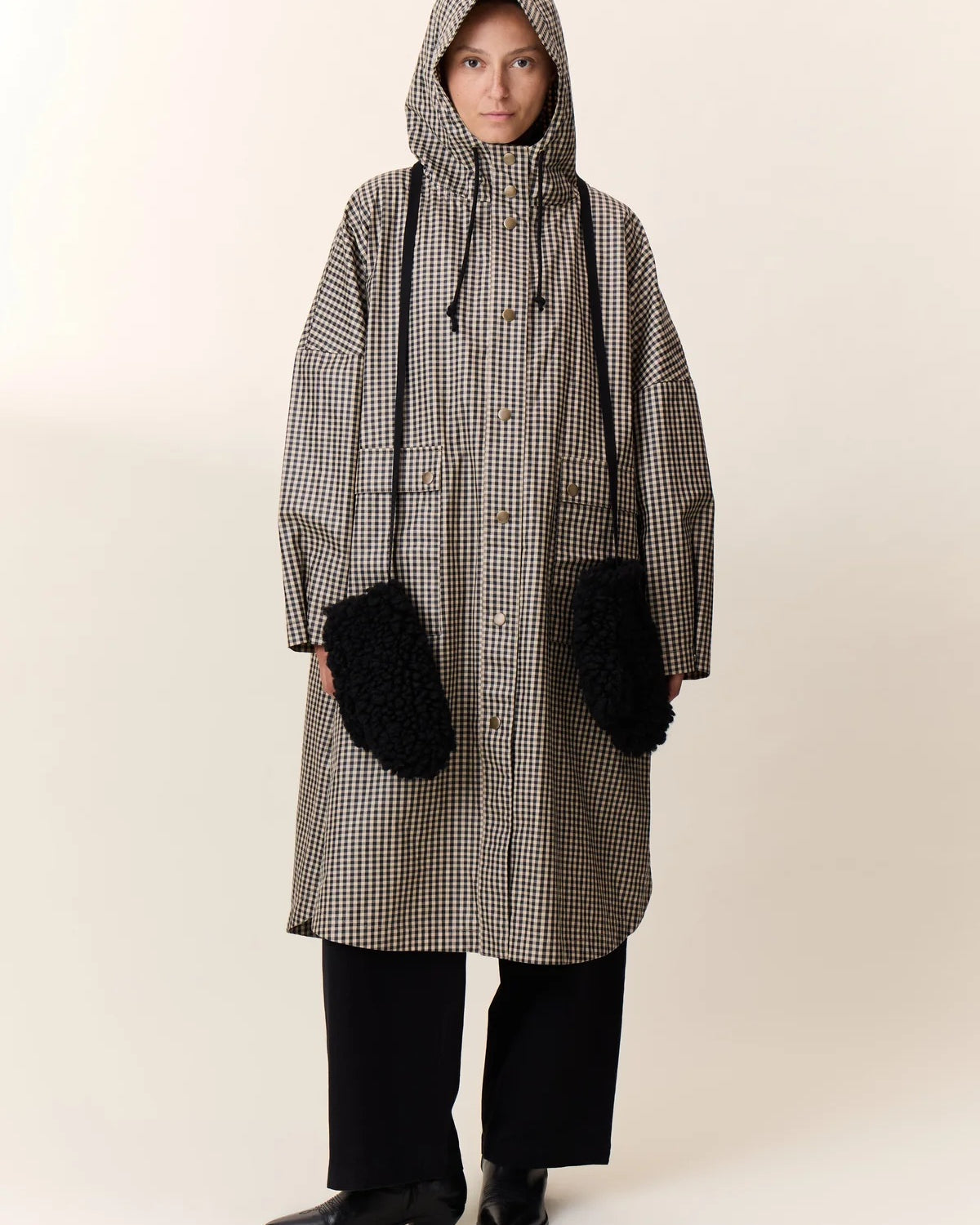 Person wearing a long checkered coat with a hood on a white background