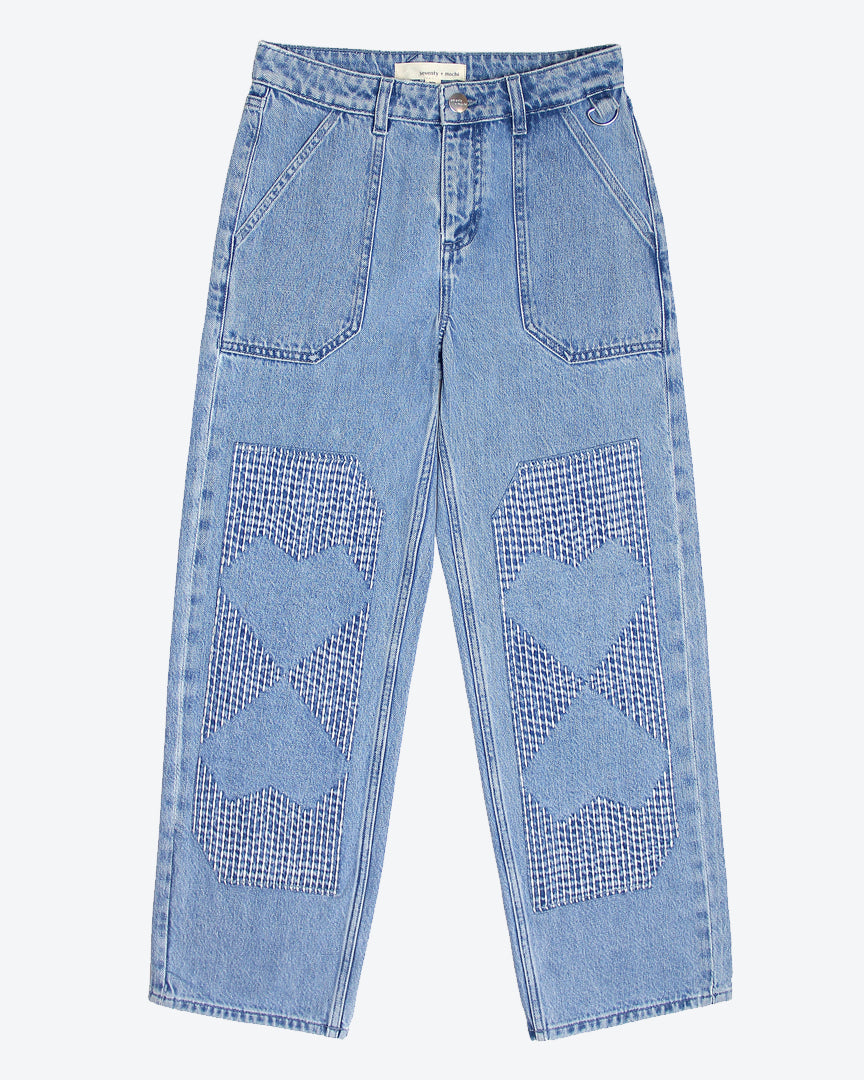 A pair of straight-leg blue jeans with carpenter style patches and embroidery stitches in the shape of hearts on the front legs.