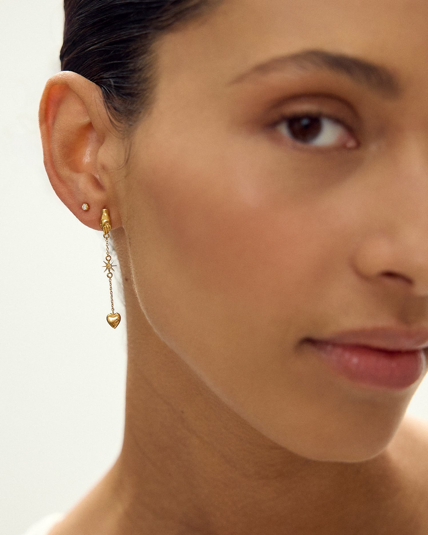 Close-up of a woman wearing gold earrings with a neutral background