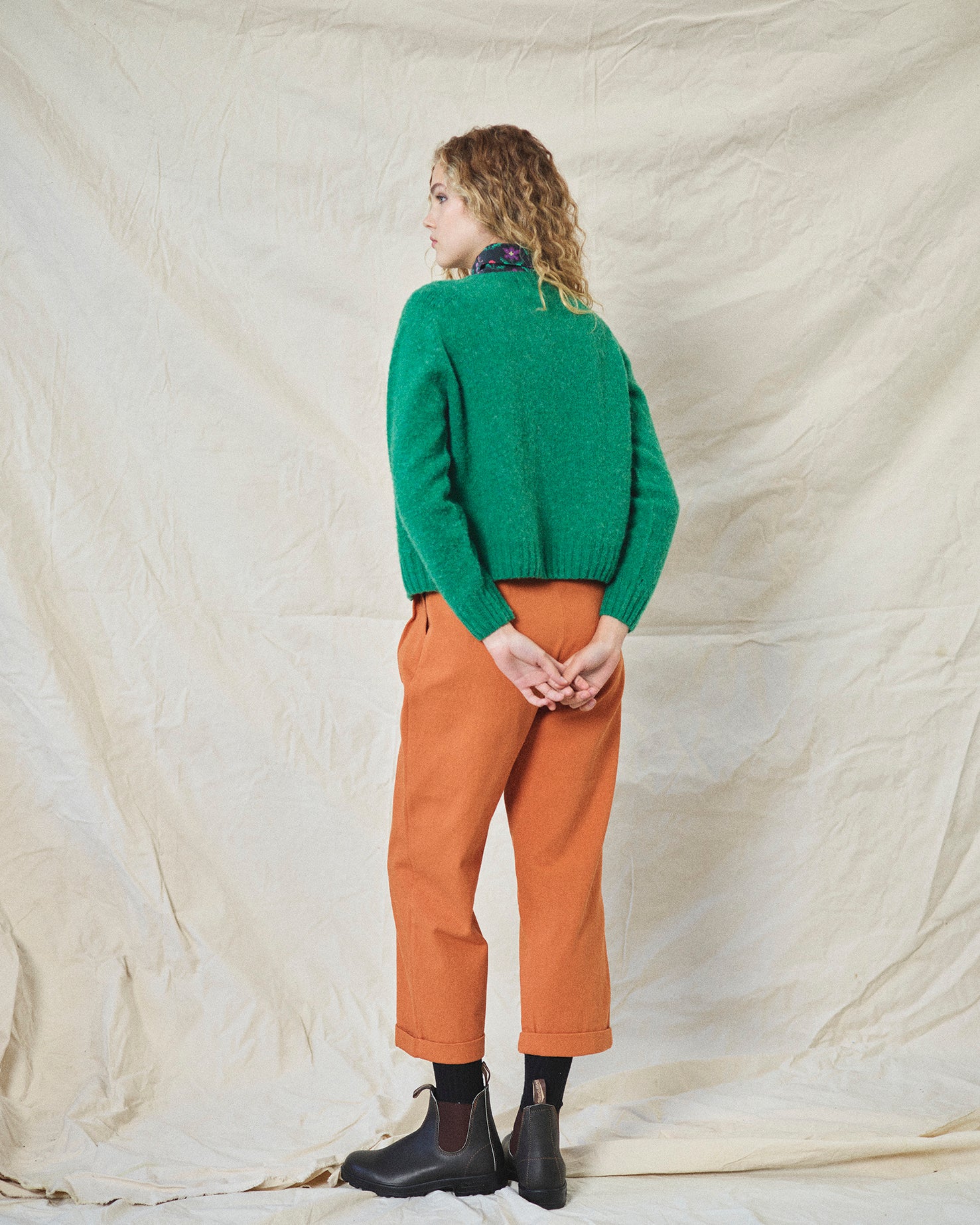 A pair of orange wide leg trousers with pleats and a fixed turn-up hem, made from cotton drill fabric.